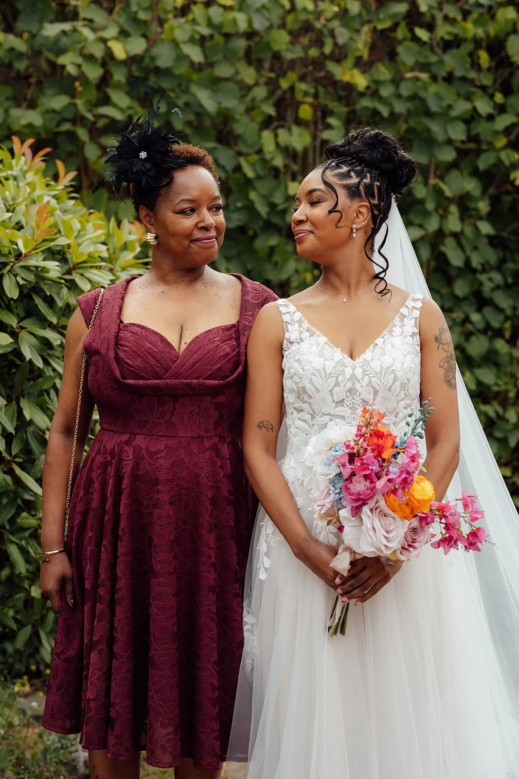Larisha sharing a warm moment with a wedding guest while holding her bright bridal bouquet in the gardens at Oaks Farm Weddings in Surrey.