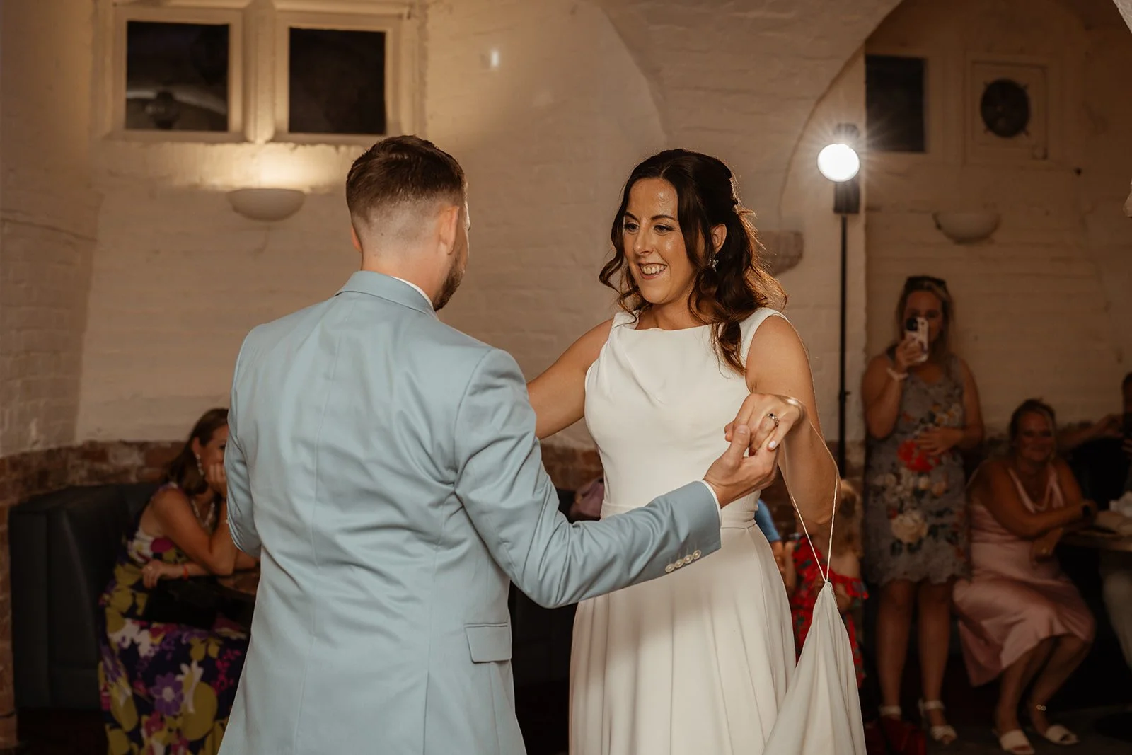 Michelle and Andy share their first dance during their evening wedding celebration at Crowcombe Court in Somerset, UK, surrounded by friends and family.