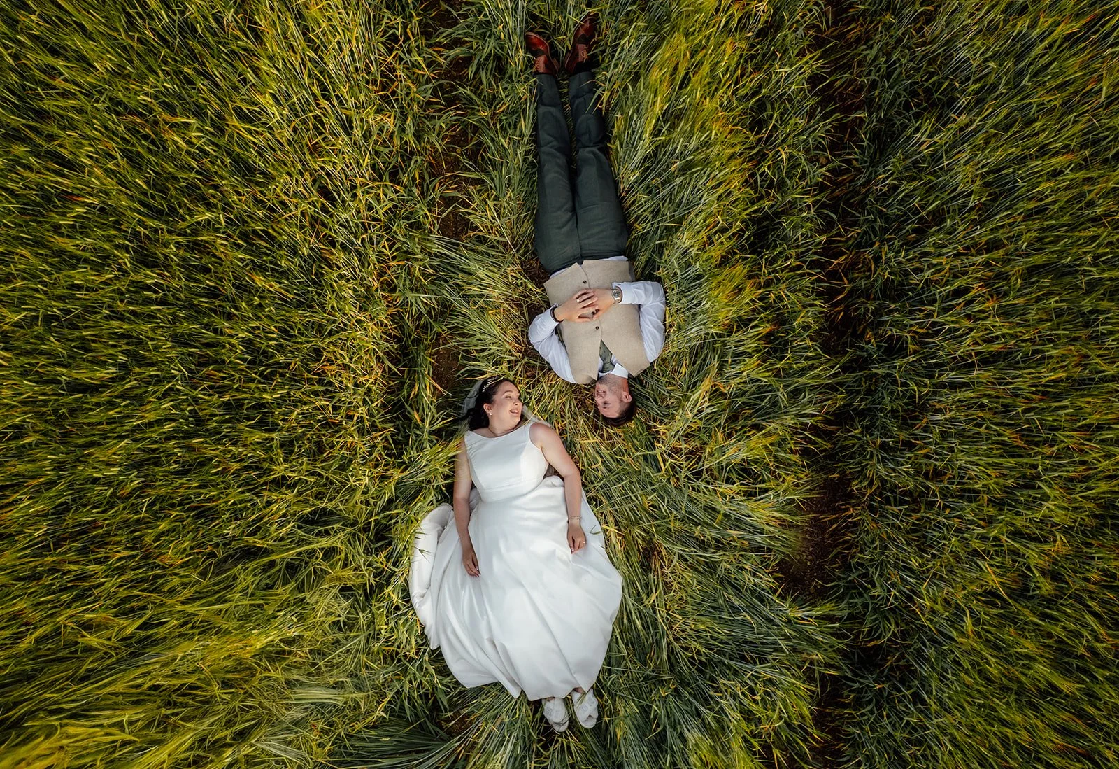 Aerial portrait of Chloe & Armani lying together in a field at The Barn at Upcote in the Cotswolds, photographed by Just James Weddings.
