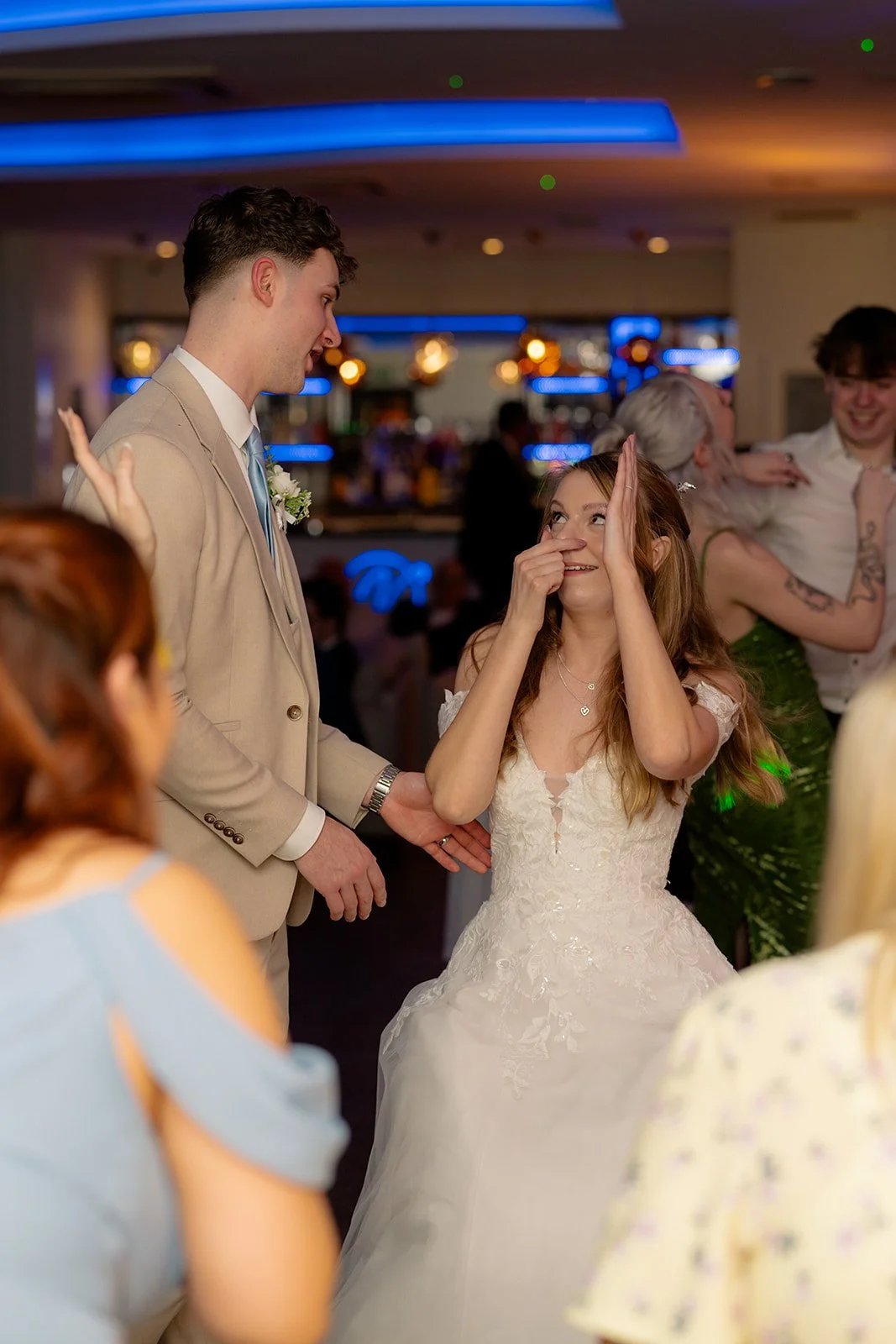 Hannah & Cameron dance together on the lively reception dance floor at Sandy Cove Hotel in North Devon. Guests celebrate around the couple while colourful lighting fills the bar area during the evening party.