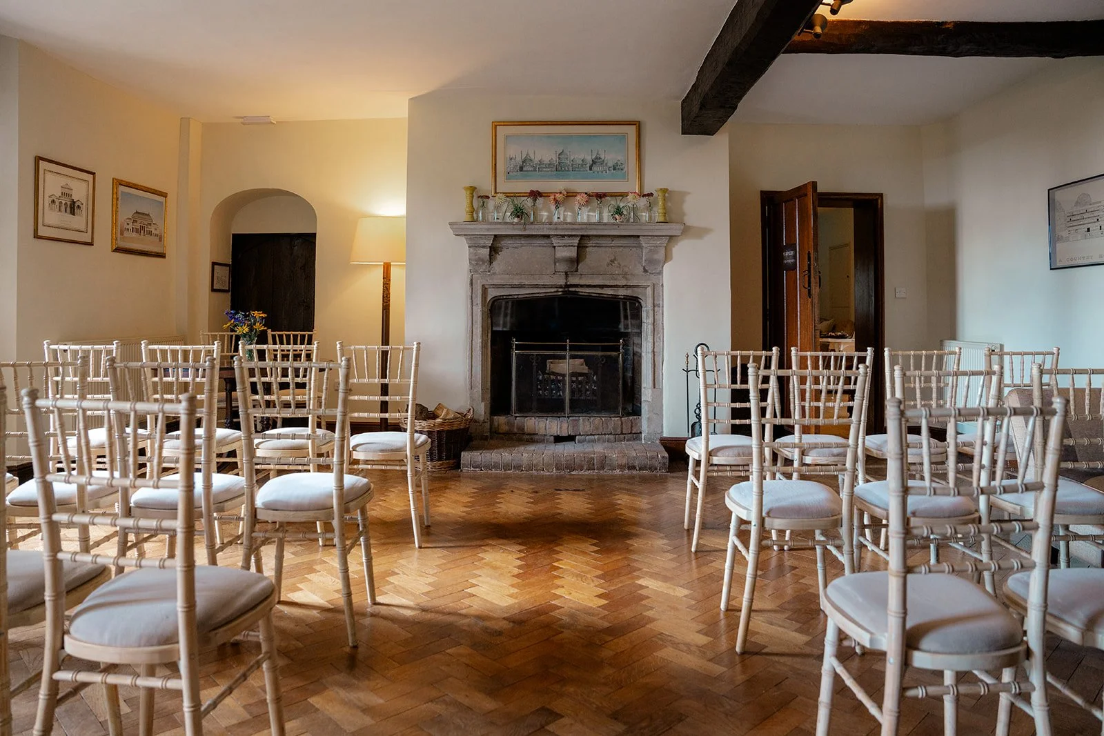 Indoor ceremony room at Broadfield Court in Herefordshire, with white chairs, parquet flooring, fireplace and traditional country house details, photographed by Just James Weddings.