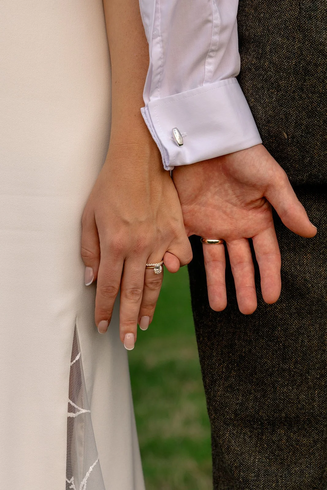 Close up of Abi & Josh’s wedding rings and hands at The Cider Barn in Somerset, with the bride’s engagement ring and groom’s wedding band photographed by Just James Weddings for natural wedding detail photography.