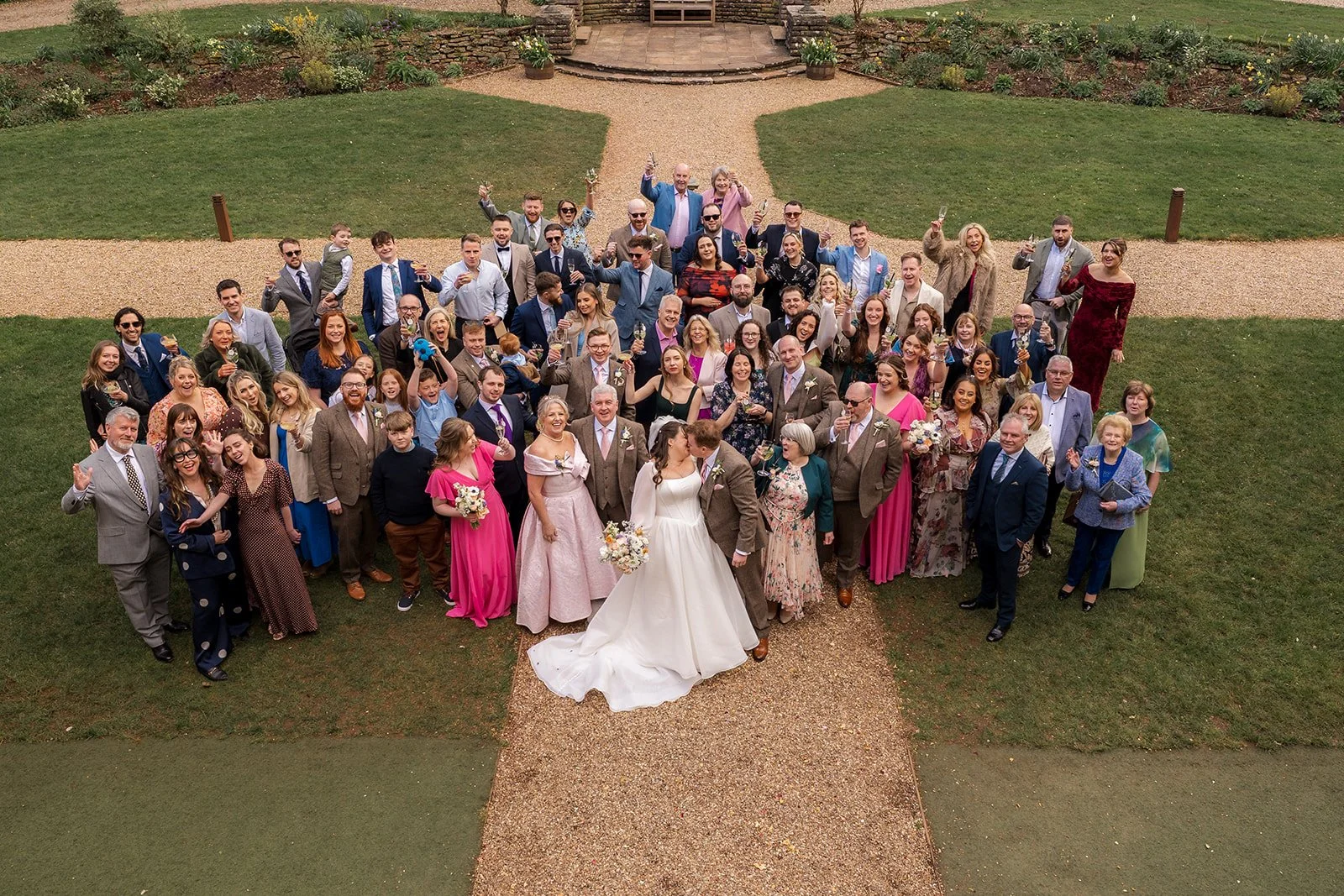 Emily & Josh stand at the centre of a large wedding guest group photo at Coombe Lodge Blagdon, Somerset, UK, surrounded by friends and family on the garden paths.