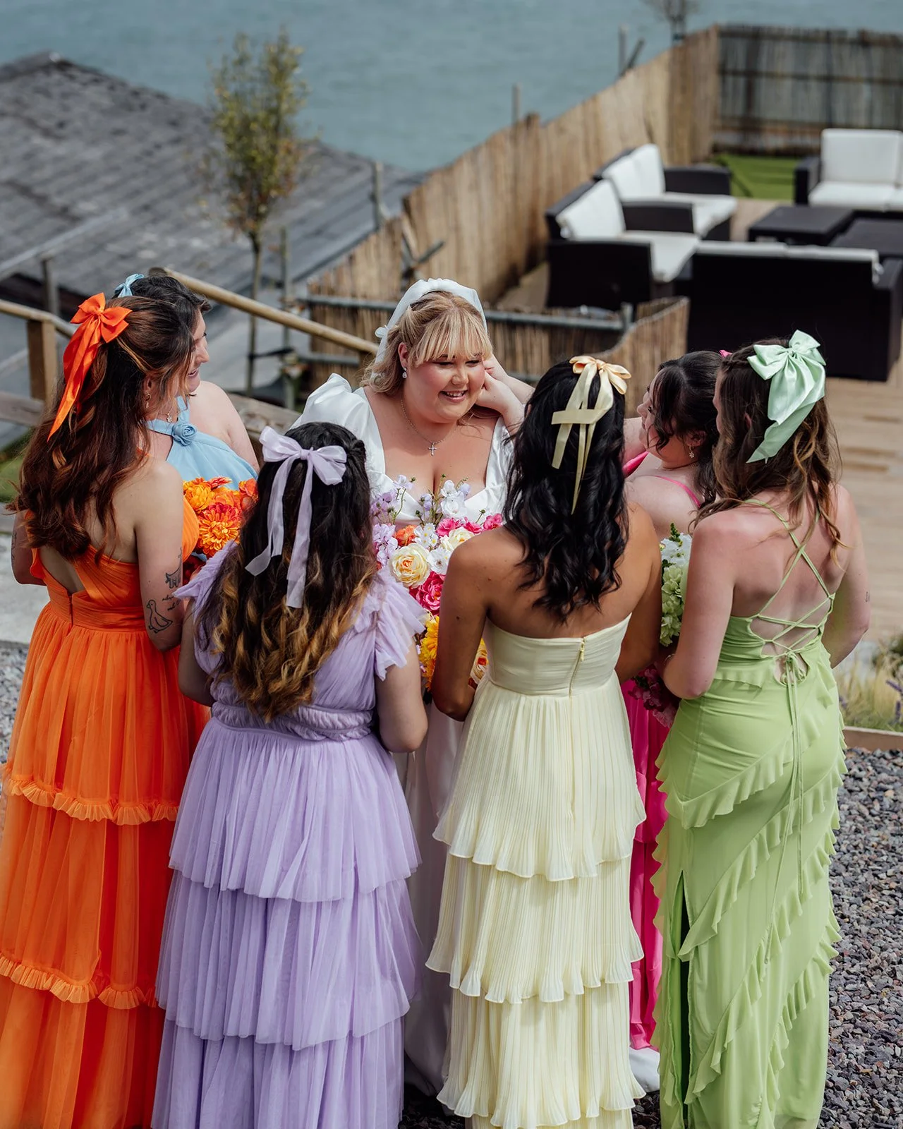 Holly smiles with her bridesmaids in colourful dresses and matching hair bows before the ceremony at Sandy Cove Hotel in North Devon, photographed by Just James Weddings.