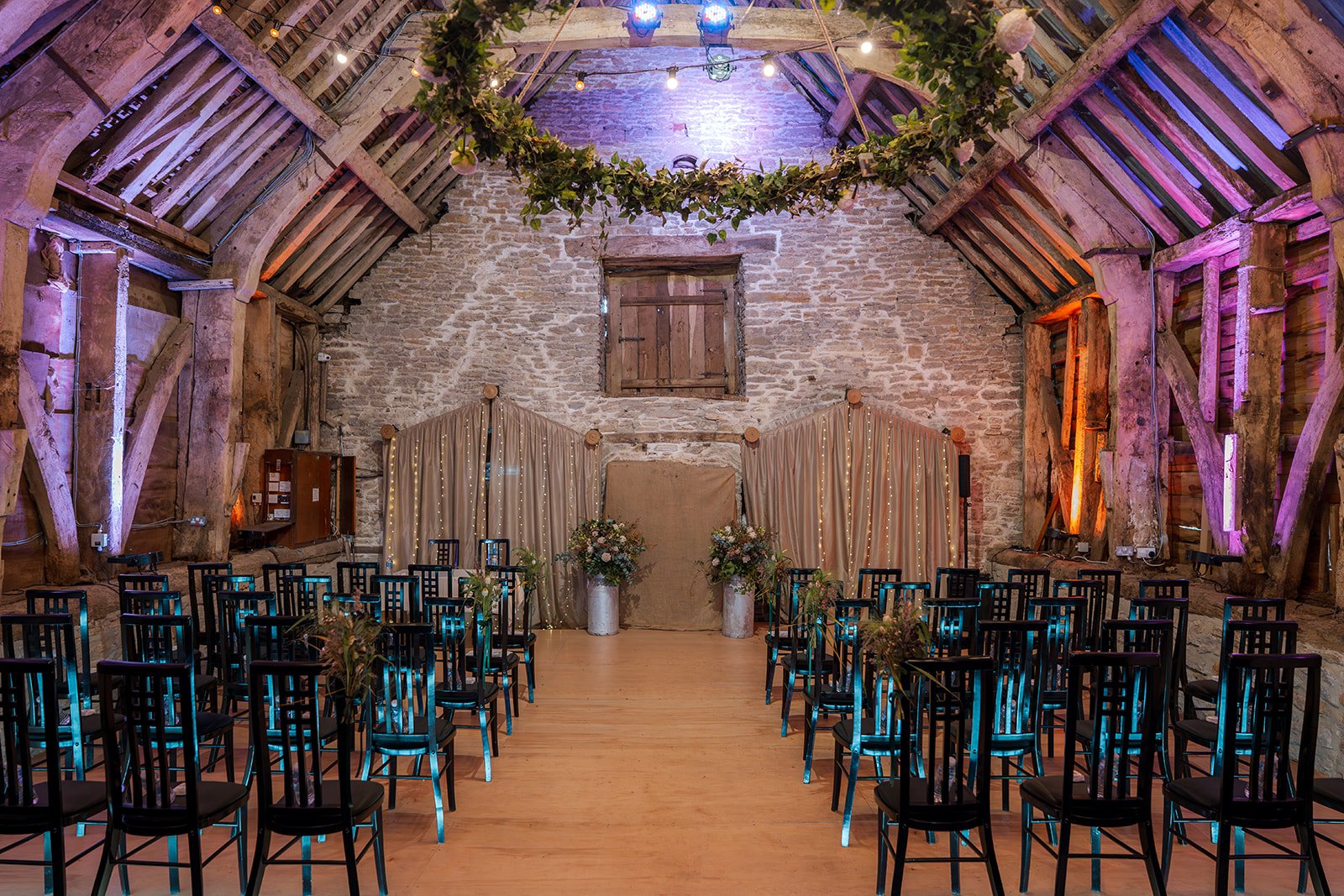 Indoor ceremony setup at Stockbridge Farm Barn in Dorset, with wooden chairs, exposed beams, stone walls and autumn styling, photographed by Just James Weddings for rustic wedding venue inspiration.