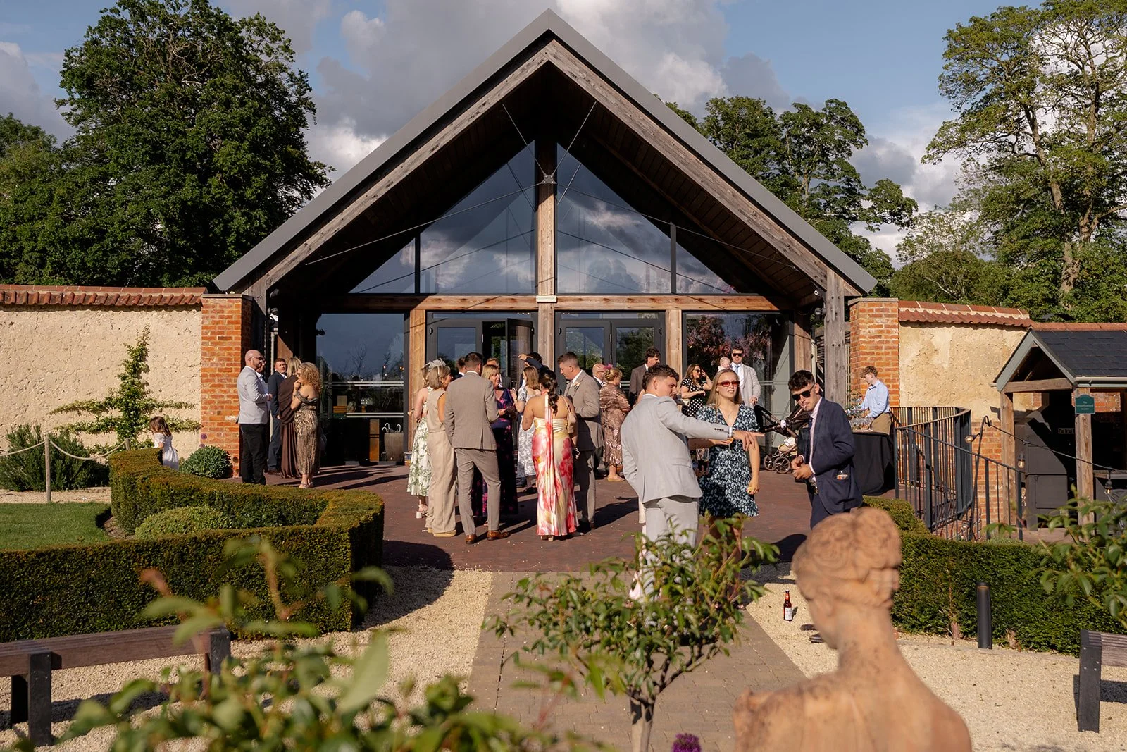 Wedding guests gathered outside the reception building at Syrencot in Wiltshire, photographed by Just James Weddings for relaxed drinks reception and venue atmosphere.