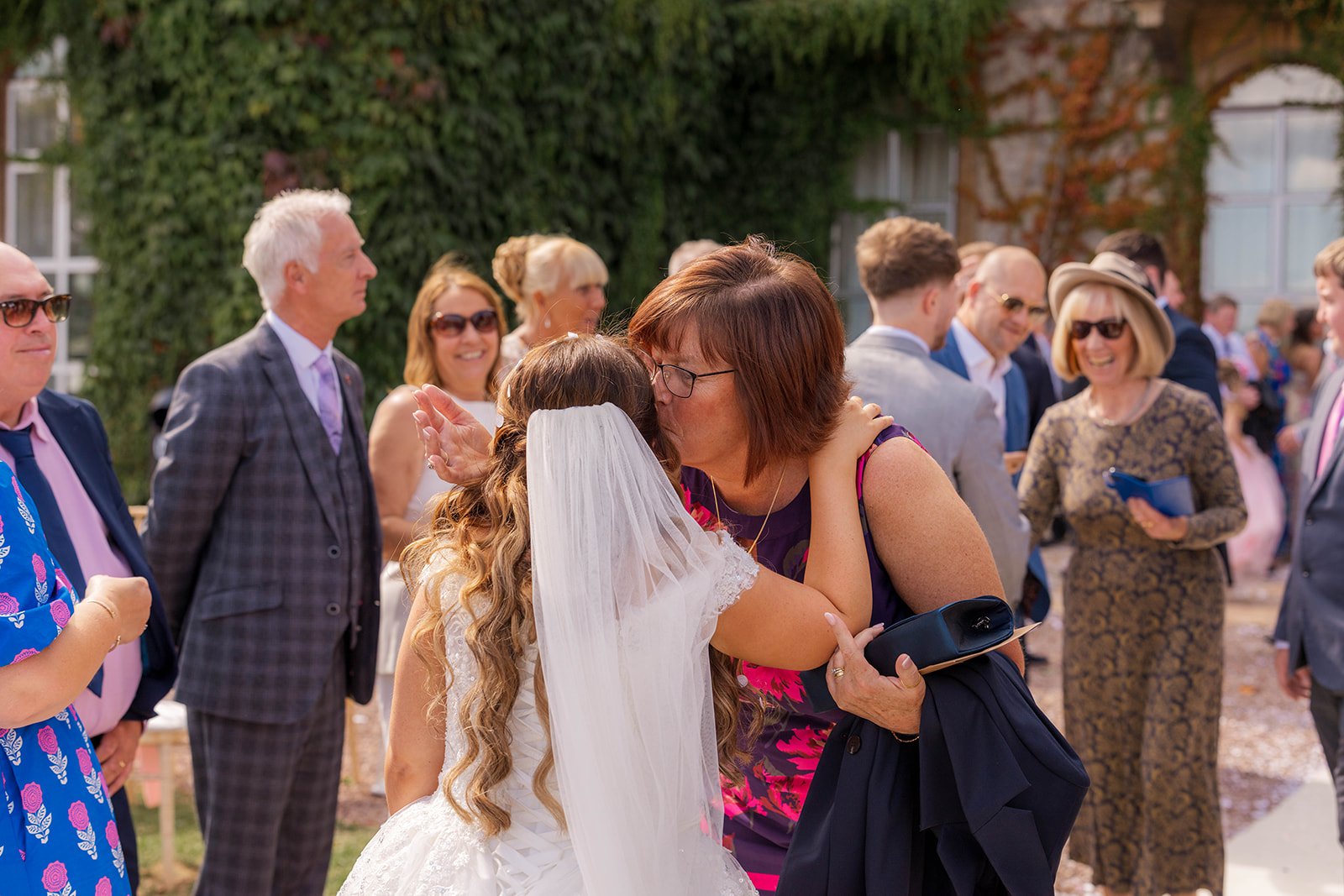Rhiannon hugging a guest during the drinks reception at Eastwood Park in Gloucestershire, photographed by Just James Weddings for candid documentary wedding moments.