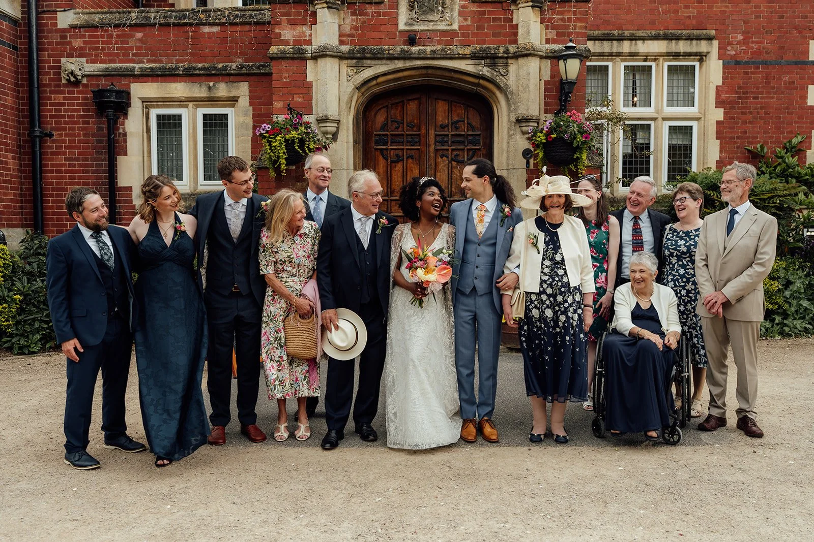 Melody & Jonny laugh with family members during a group portrait outside Berwick Lodge in Bristol, photographed by Just James Weddings.