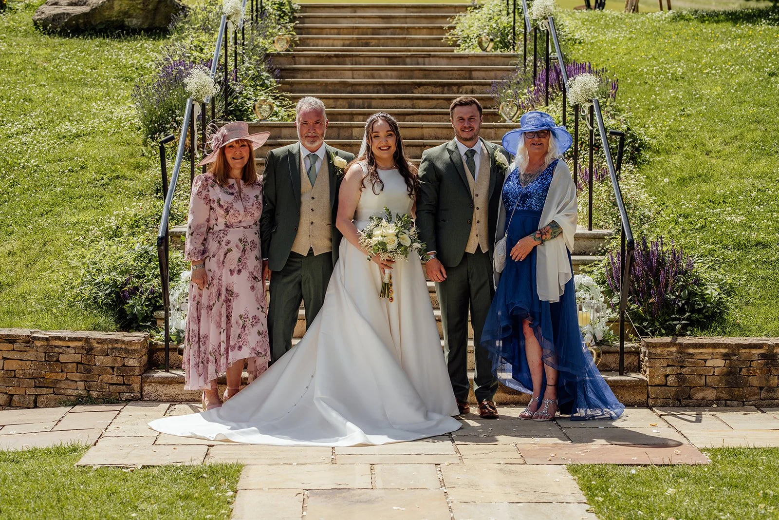 Chloe and Armani pose with their parents in the gardens at The Barn at Upcote in Gloucestershire after their wedding ceremony, photographed by Just James Weddings.