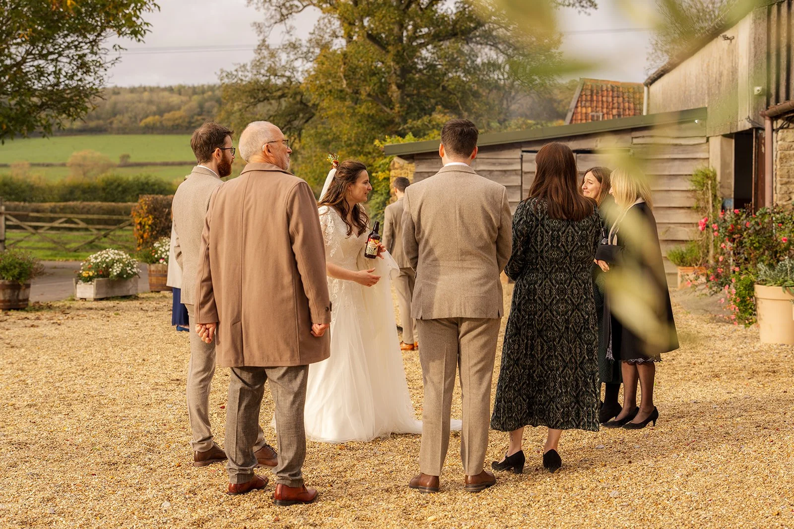 Maisie & Andrew chatting with guests in the courtyard at Stockbridge Farm Barn in Dorset, photographed by Just James Weddings for relaxed autumn wedding reception moments.