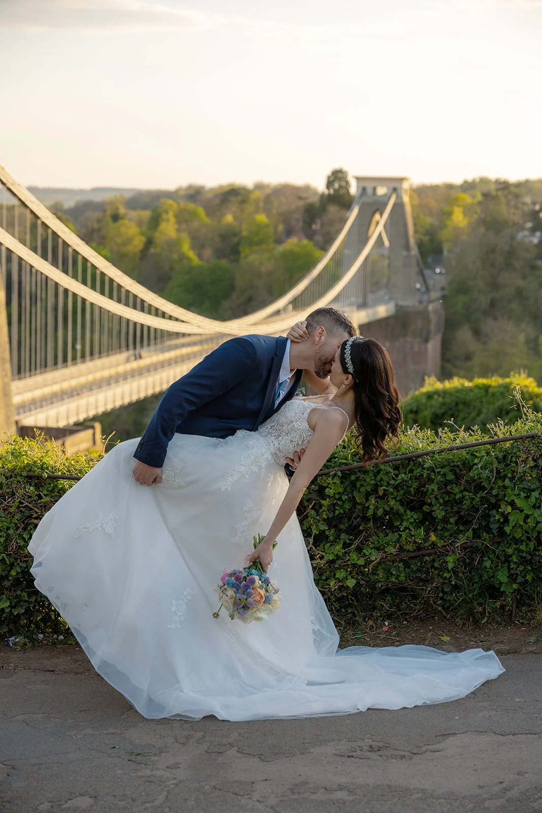 Carmelo dips Ruth for a kiss with Clifton Suspension Bridge stretching behind them in Bristol, UK, creating a romantic golden-hour wedding portrait near No. 4 Clifton Village.