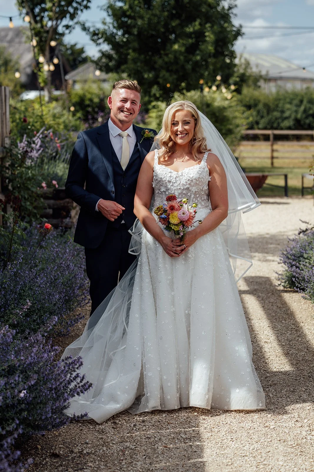 Elise and Tom smiling together during relaxed wedding portraits in the gardens at Bowerchalke Barn in Wiltshire, photographed by Just James Weddings.