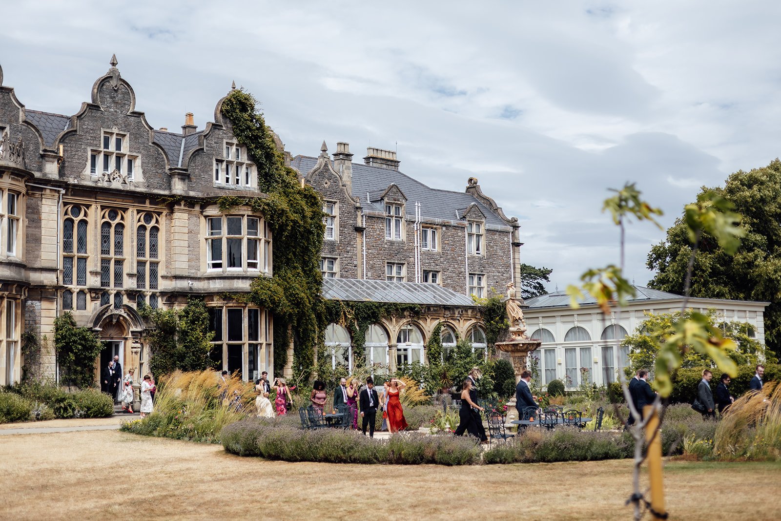 Exterior view of Clevedon Hall in Somerset, with guests gathered in the gardens outside the historic manor house, photographed by Just James Weddings.