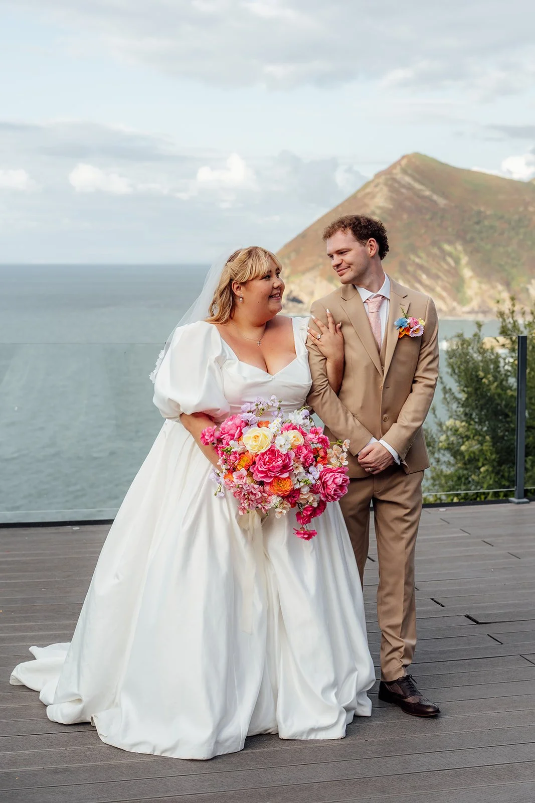 Holly & Alex pose together with the dramatic North Devon coastline behind them at Sandy Cove Hotel, photographed by Just James Weddings.