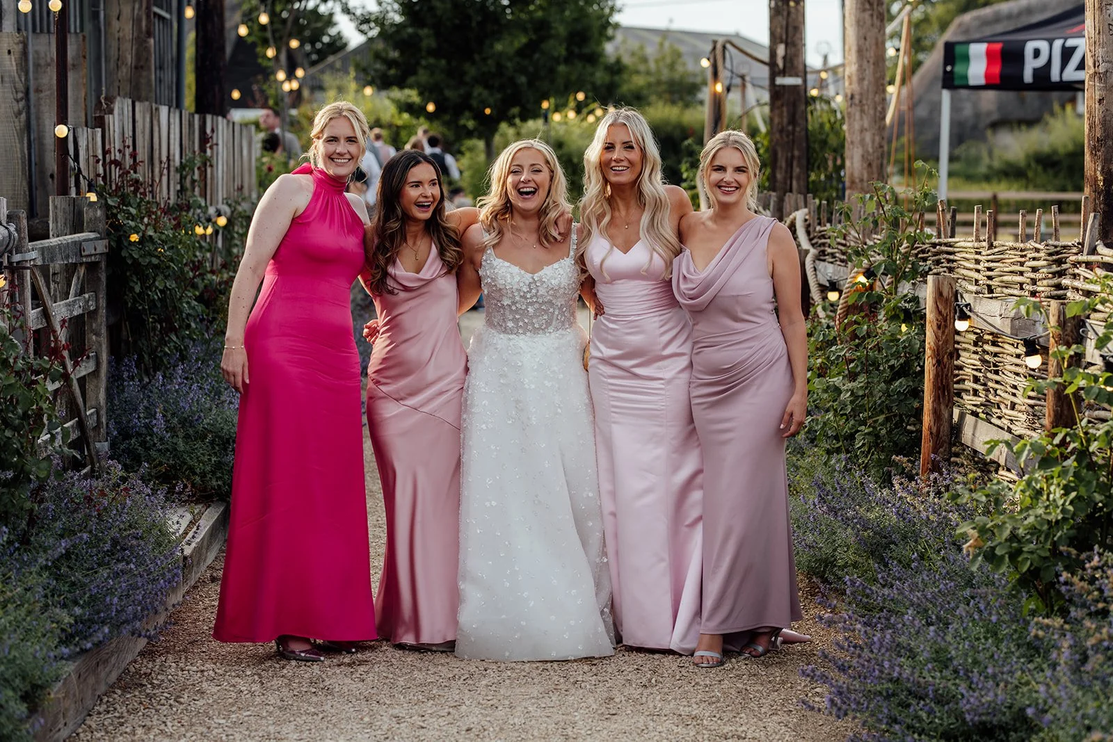 Elise smiling with her bridesmaids in pink dresses during wedding party portraits at Bowerchalke Barn in Wiltshire, photographed by Just James Weddings.