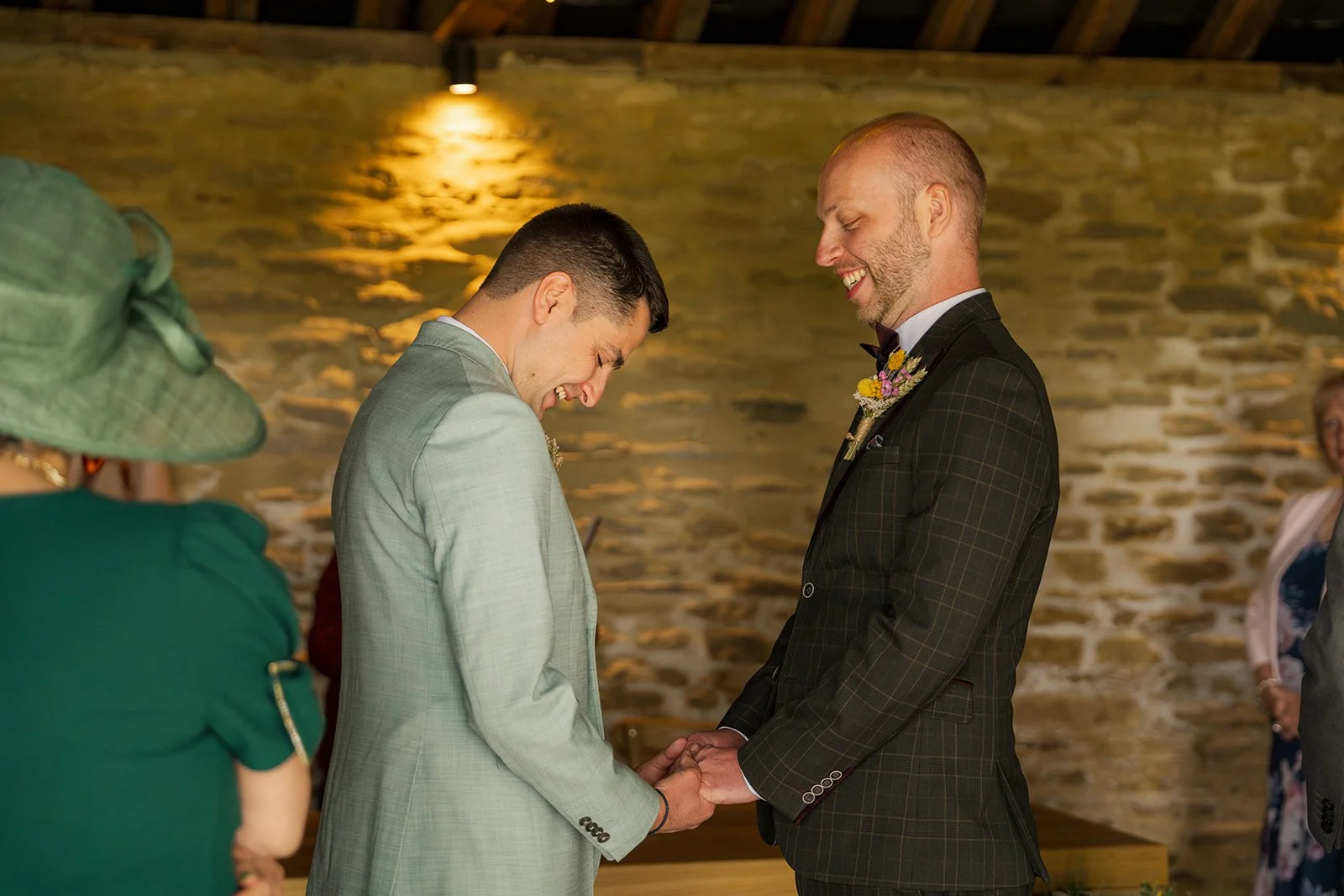 Sam & Gavin holding hands during their ceremony at The Great Barn at Aynho in the Cotswolds, photographed by Just James Weddings for emotional wedding ceremony photography.