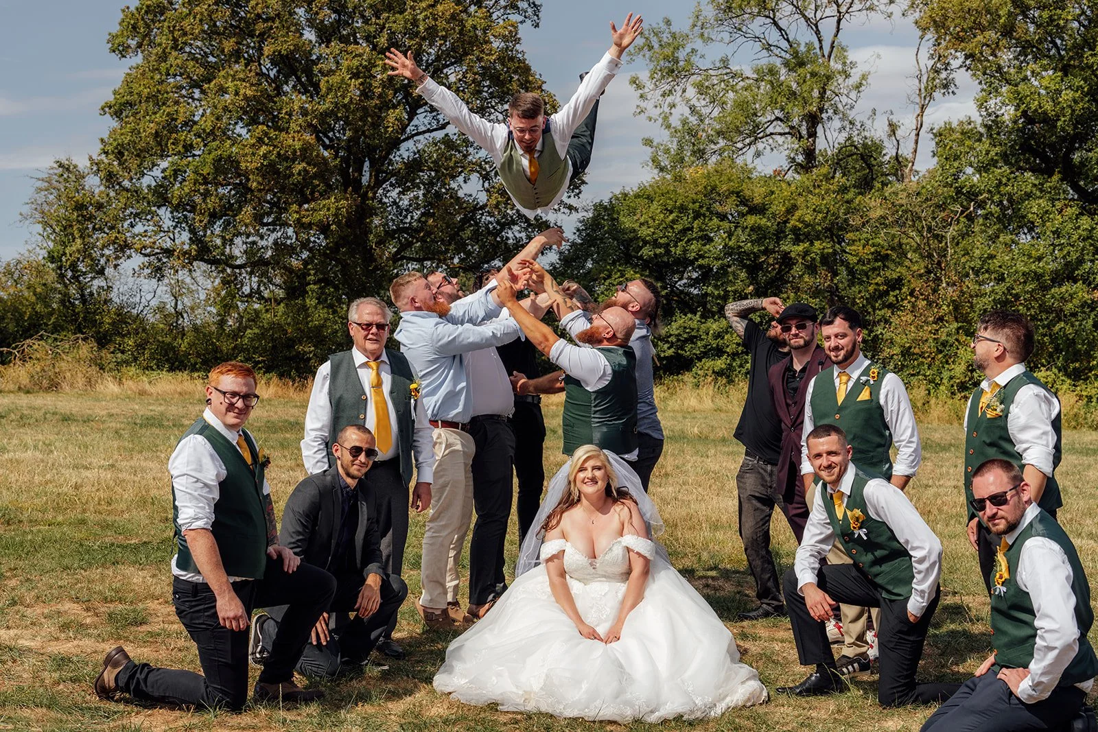 Matthew being tossed into the air by friends during a fun wedding party photo with Lucy at Curated Canvas at Noah’s Pond in Somerset, photographed by Just James Weddings.