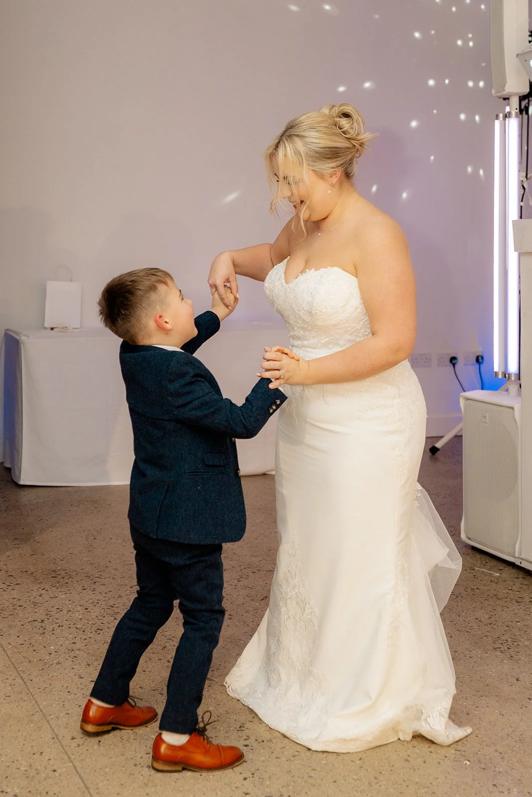 Daisy dancing with her son at Andrew & Daisy’s Sandy Cove Hotel wedding in Devon, smiling beneath soft reception lighting, capturing heartfelt mother and son moments on the dance floor at this seaside wedding venue.