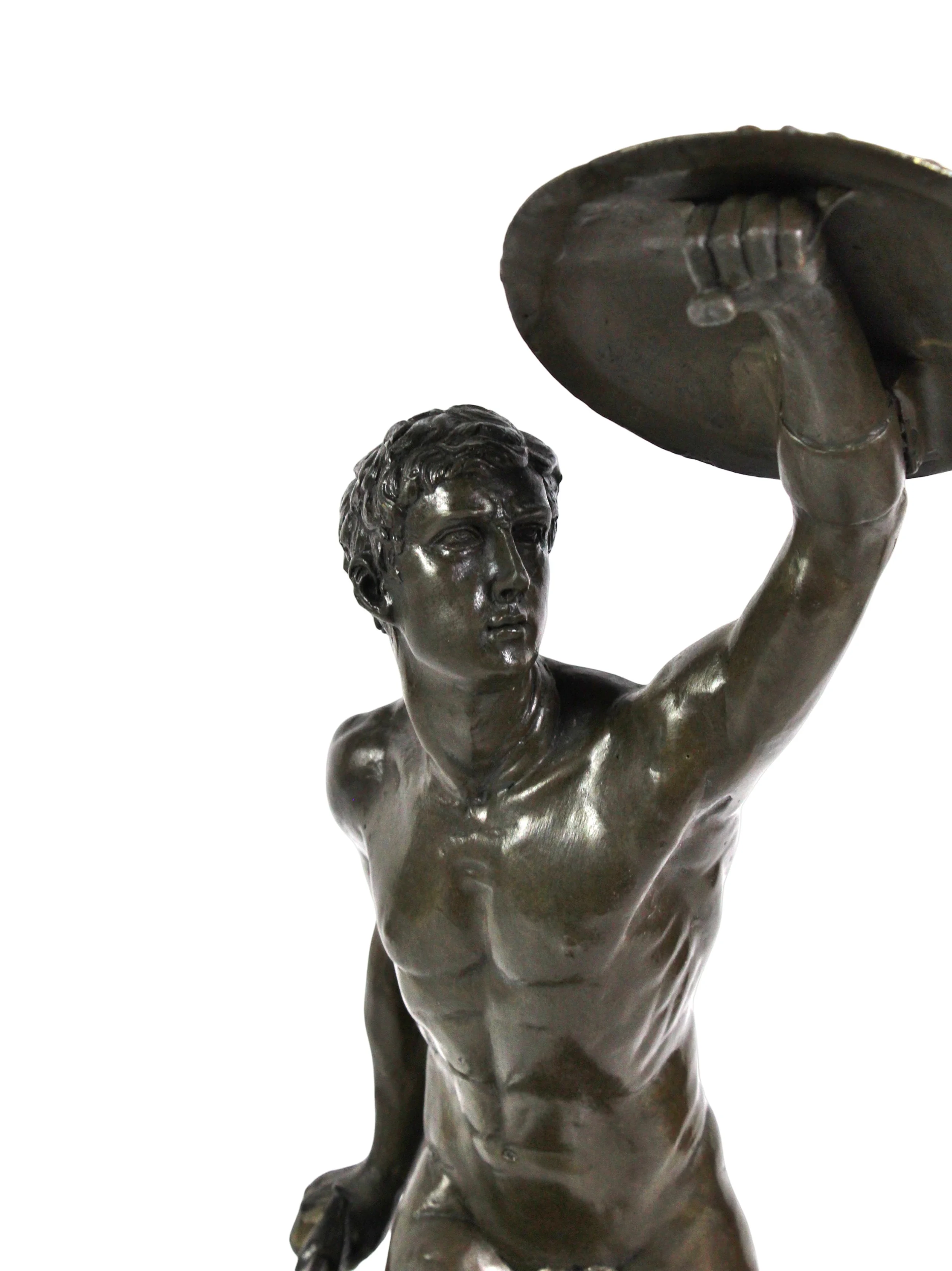 Dark brown statue of a nude male soldier holding a shield and sword standing on a pink marble base