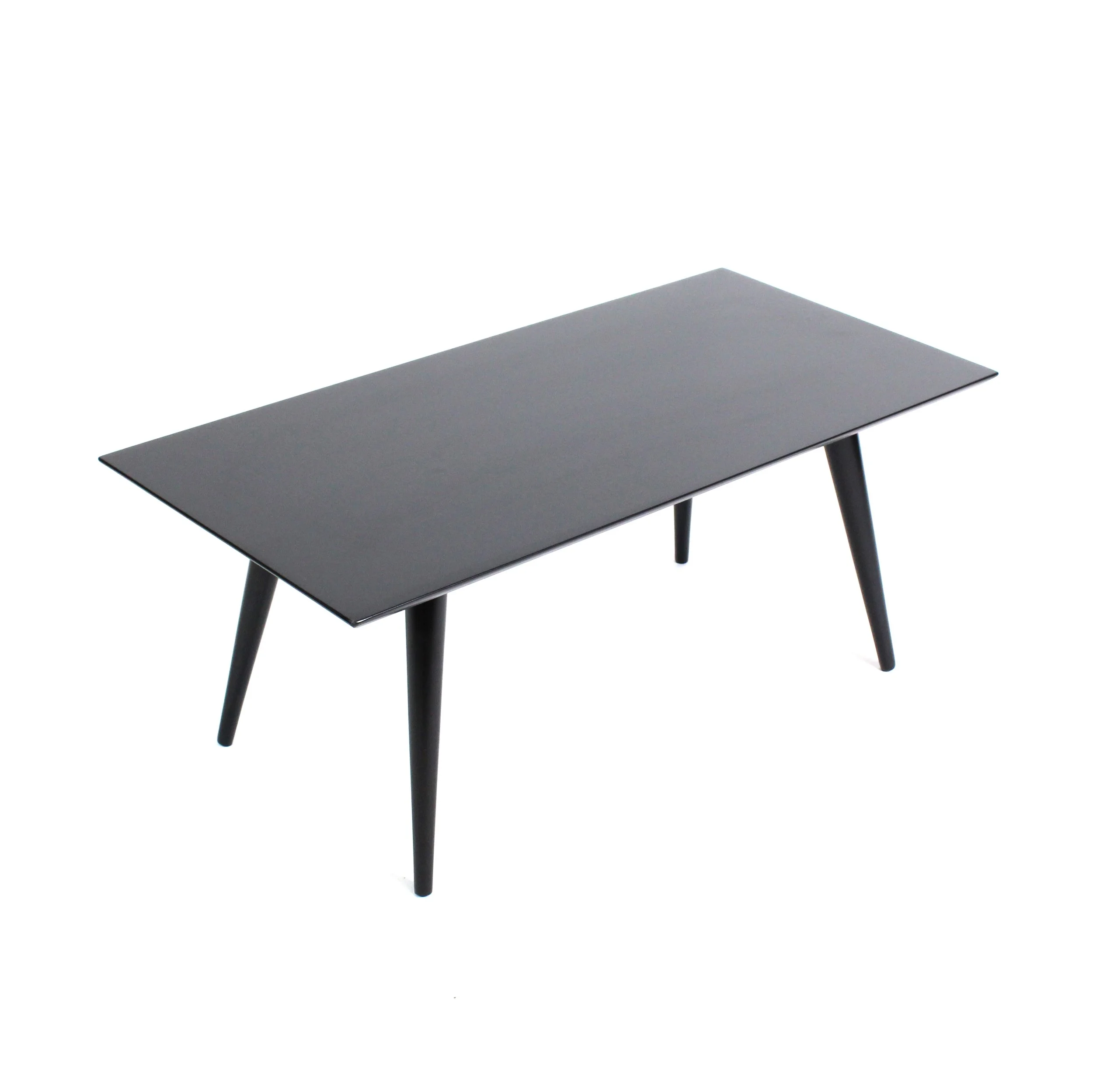 a matte black coffee table with a beveled underside edge and four splayed tapered legs