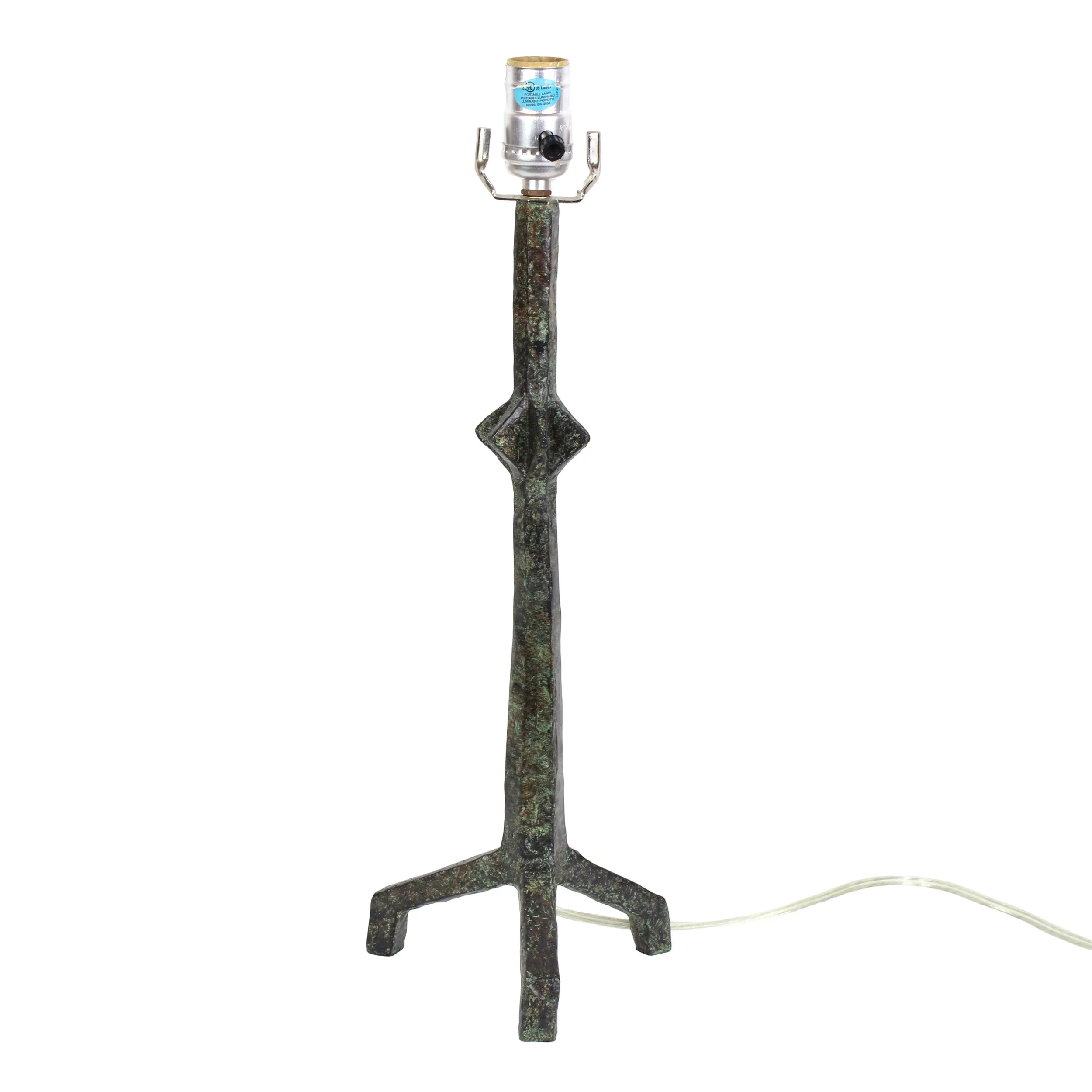 A metal and green speckled metal table lamp with a three legged base and geometric diamond pattern near the middle of the stem
