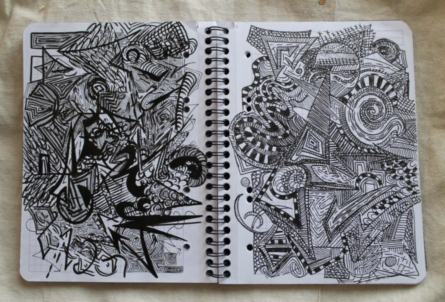 Notebook with intricate black ink doodles on both pages.