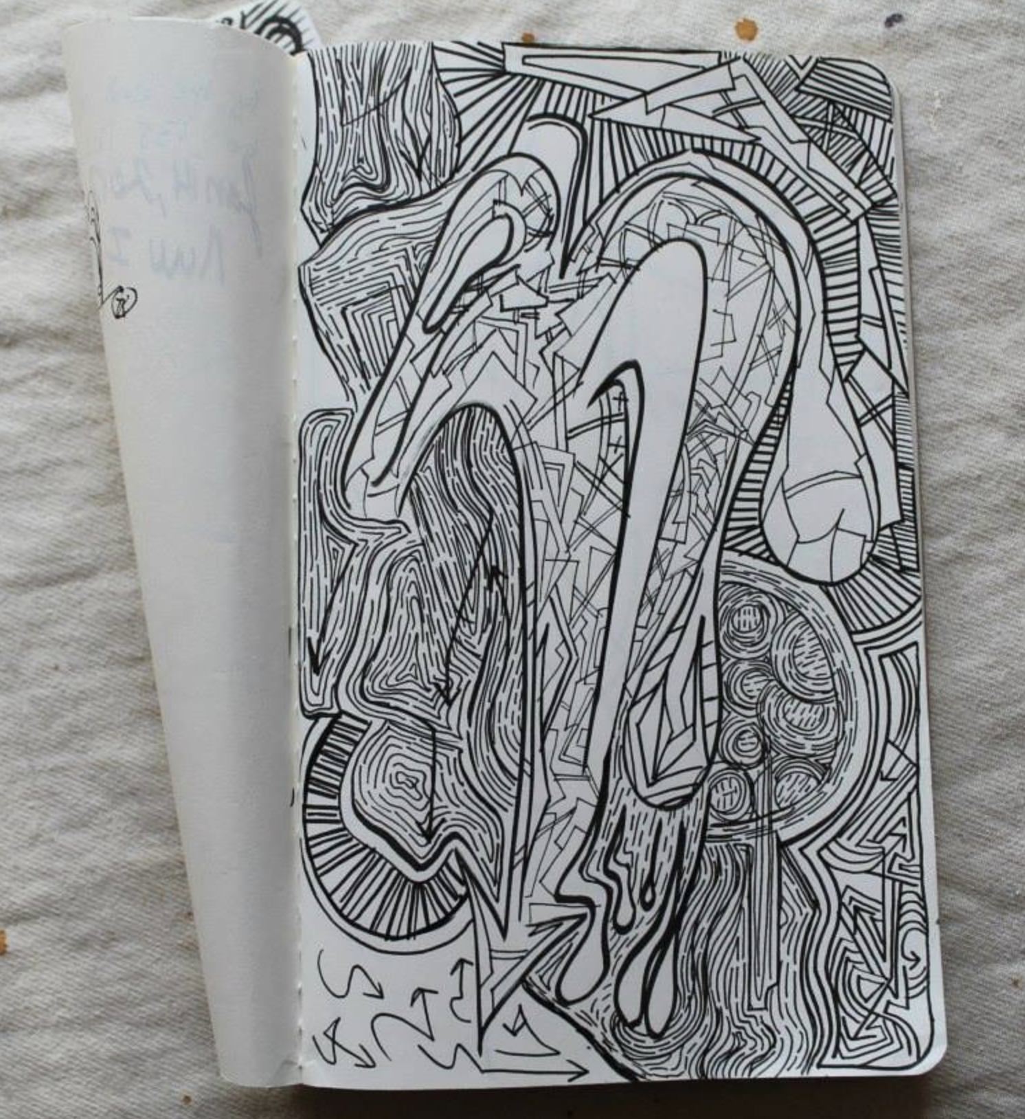 Abstract black and white line art drawing on notebook page with intricate geometric and organic shapes.