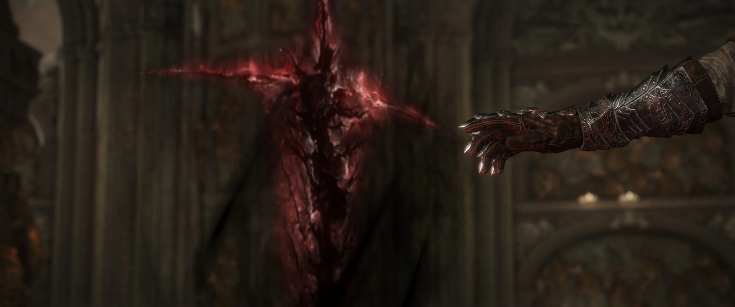 Eine dunkle Szene zeigt eine Hand in einer Rüstung, die auf eine lebendige, rote, blühende Pflanze oder Blüte vor einer alten Steinmauer zeigt.