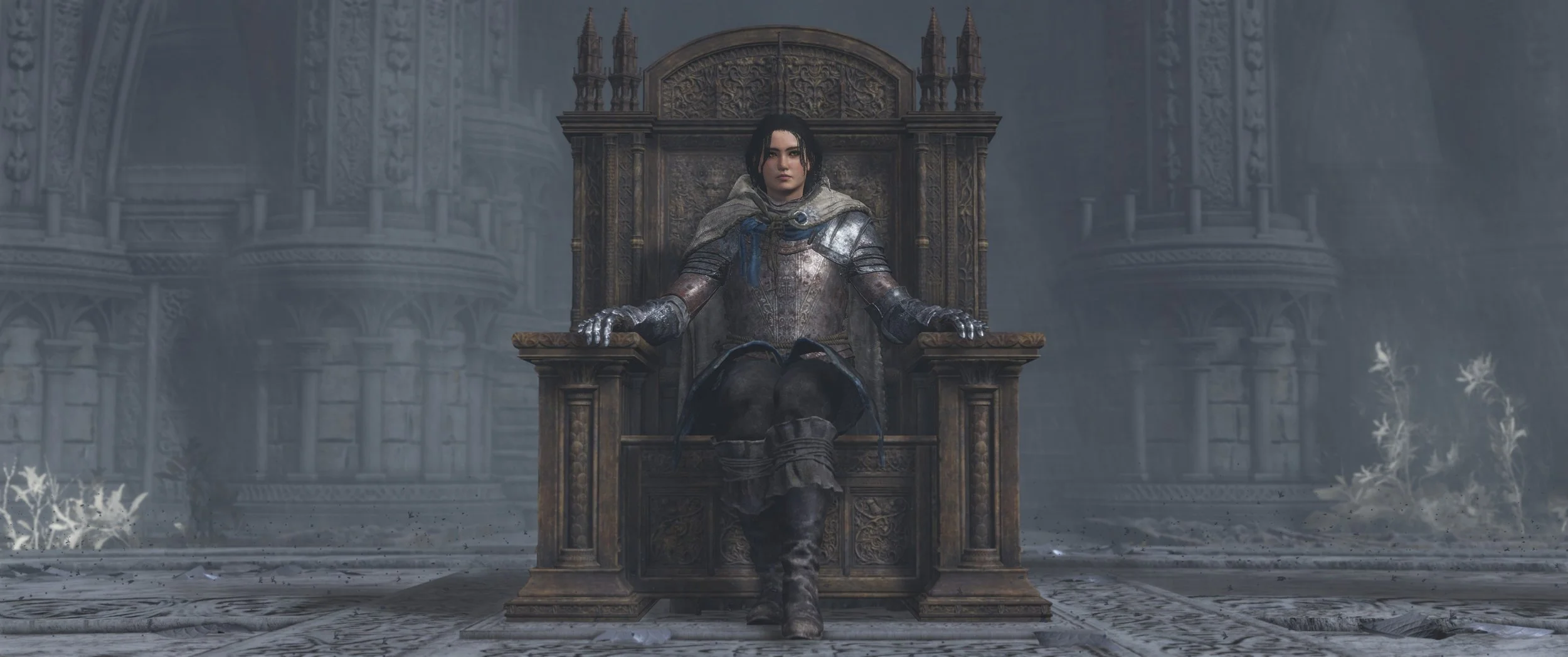 Frau in Rüstung sitzt auf einem Thron in einer kalten, steinernen, verzierten Halle.