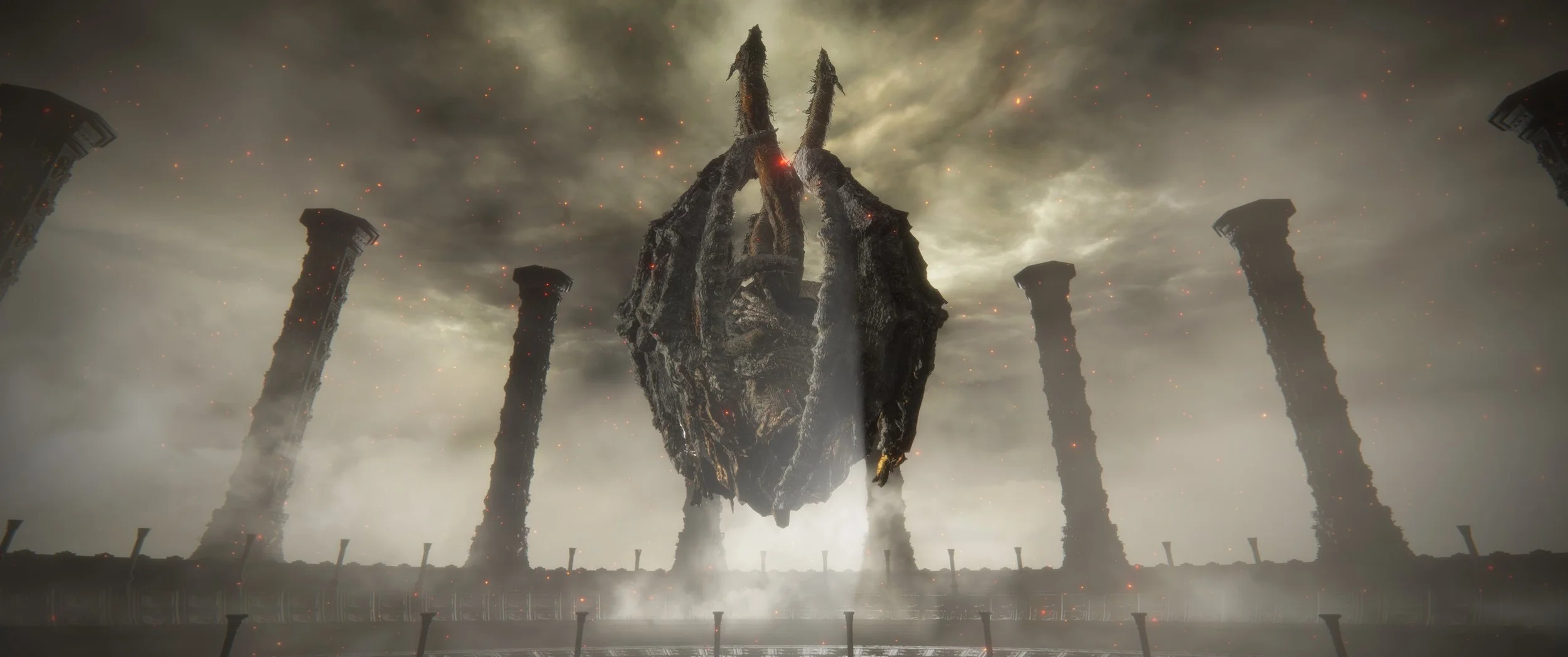 Düstere Szenerie mit sechs zerstörten, aufrecht stehenden schwarzen Stützpfeilern um einen großen, schwebenden, zerstörten, monolithischen schwarzen Gegenstand. Im Hintergrund dunkler Himmel mit Wolken und roten, glühenden Partikeln.