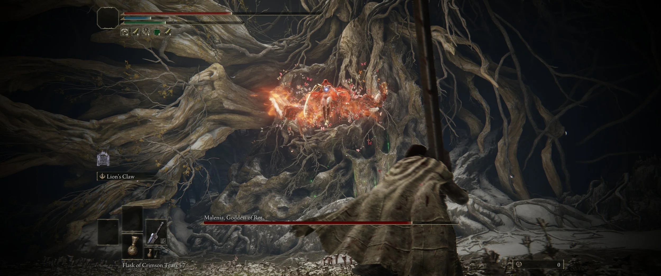 Spielszene aus dem Videospiel, in der ein Charakter einen Boss namens Malenia, Göttin des Verfalls, bekämpft. Der Charakter steht vor einem riesigen, wurzelnden Baum, während Malenia auf einem Drachen fliegt, von Flammen umgeben. Der Bildschirm zeigt