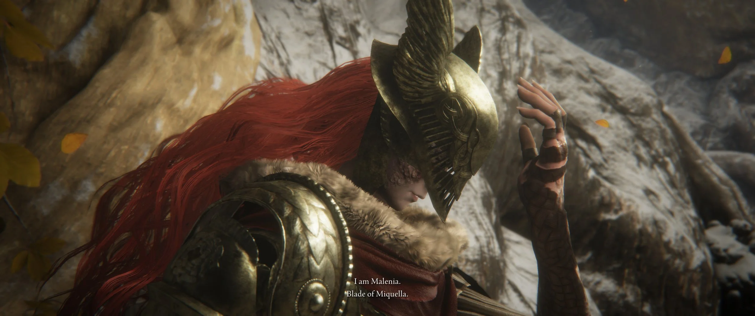 Eine verschleierte Kriegerin mit roten Haaren in goldener Rüstung, die einen Helm mit Hörnern trägt, steht vor einem Felsen und sagt: "I am Malenia. Blade of Miquella."