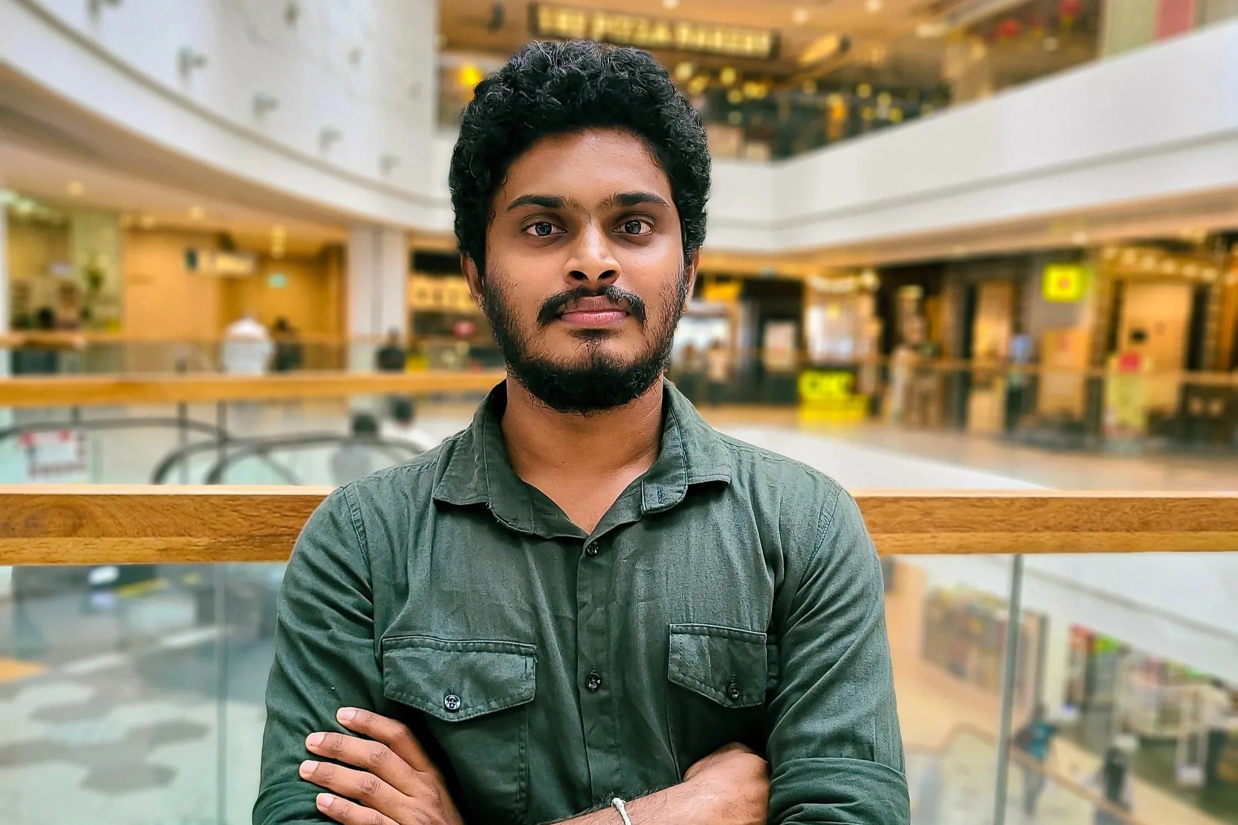 Black and white portrait of a man with a beard and curly hair, wearing a collared shirt, set against a bright yellow background.