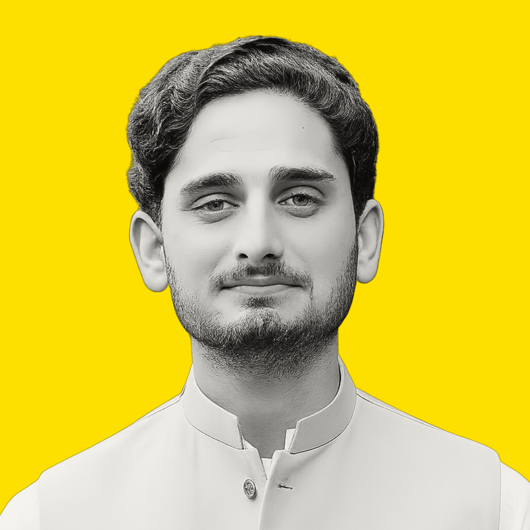 Black and white portrait of a young man wearing traditional Indian attire, standing against a bright yellow background.