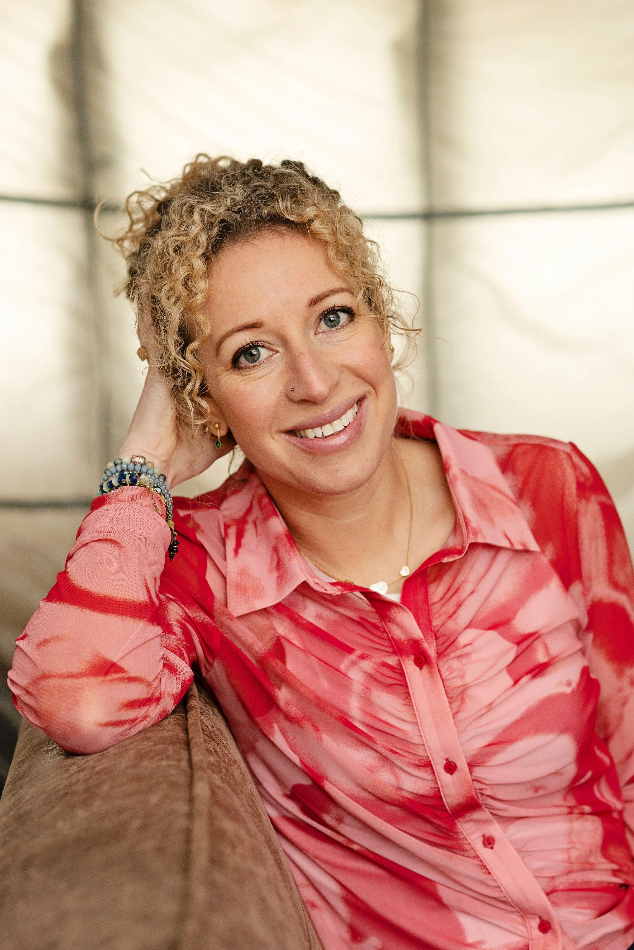 Kate Moryoussef smiling warmly, seated and relaxed in a pink floral shirt.