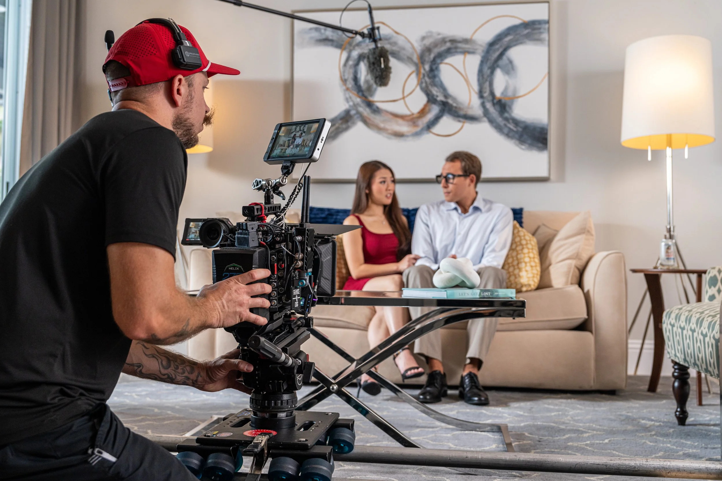 Filmmaker filming a couple sitting on a couch in a living room with modern decor.