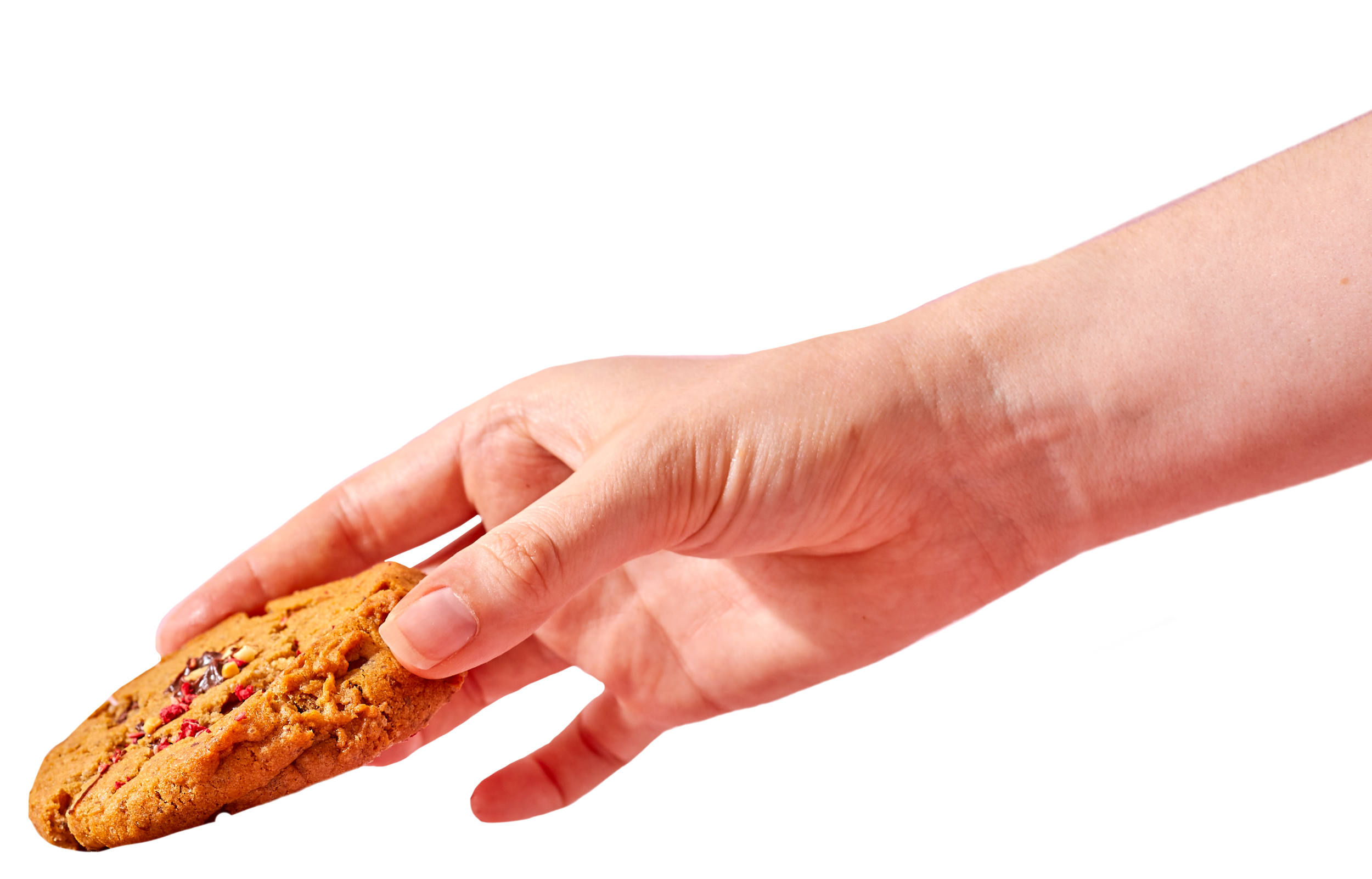 A hand reaching for a chocolate chip cookie with red and white candies, against a black background.