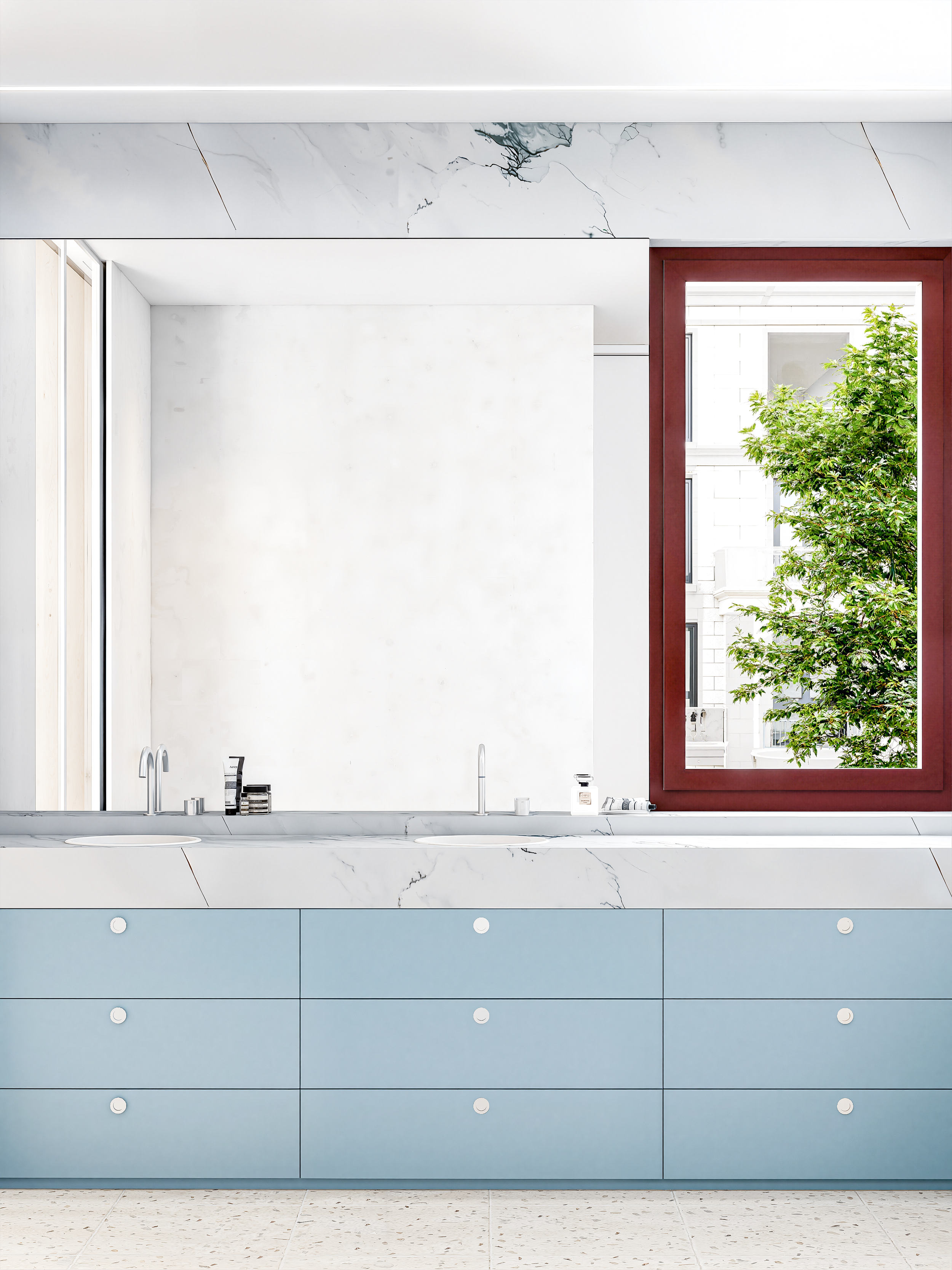 Moderne badkamer met blauwe kasten, wit marmeren wastafel, grote spiegel en een raam met een uitzicht op een groen boom.