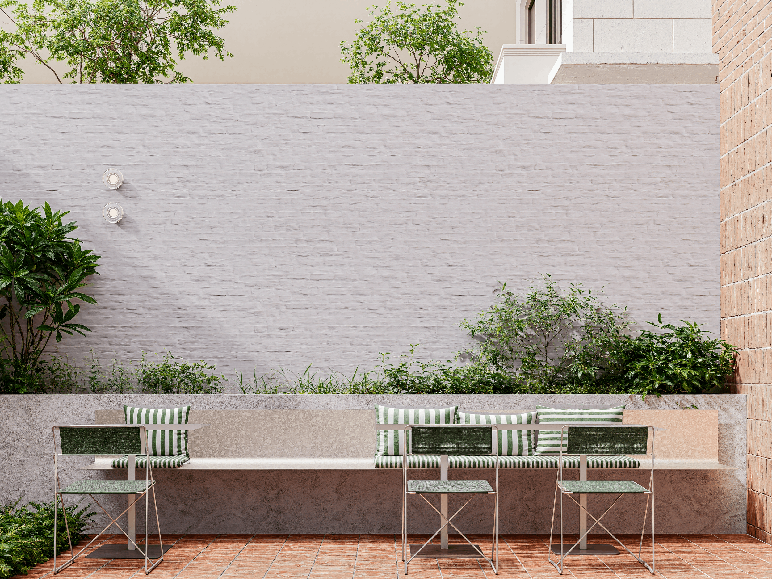 Een buitenruimte met een witte muur en een plantenbak die bedrukt is met groene en witte strepen, met enkele matzwarte stoelen en een tafel, plus groene planten en bomen in de achtergrond.