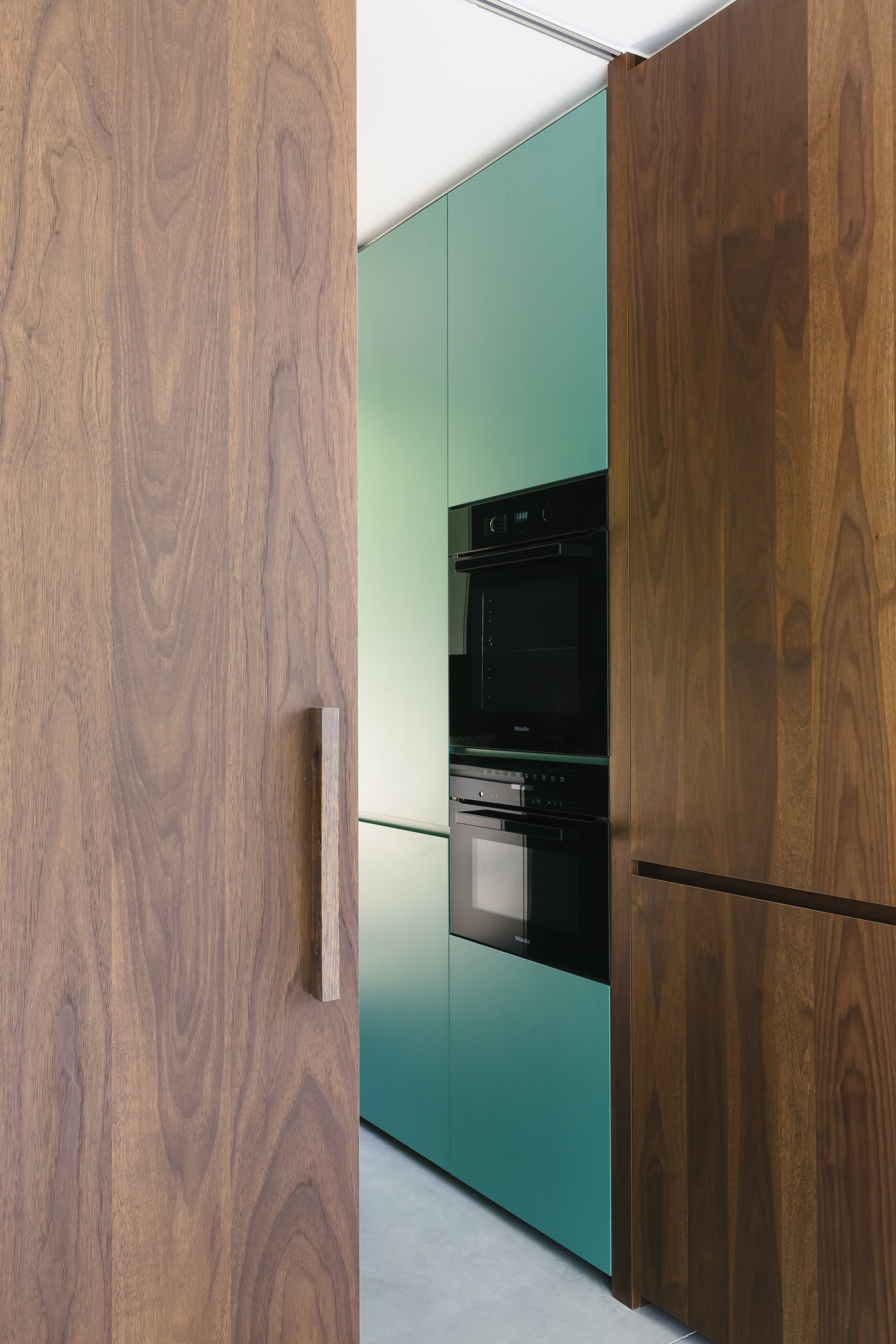 Moderne keukenkasten in een keuken met een houten werkblad en ingebouwde apparaten, waaronder een oven.