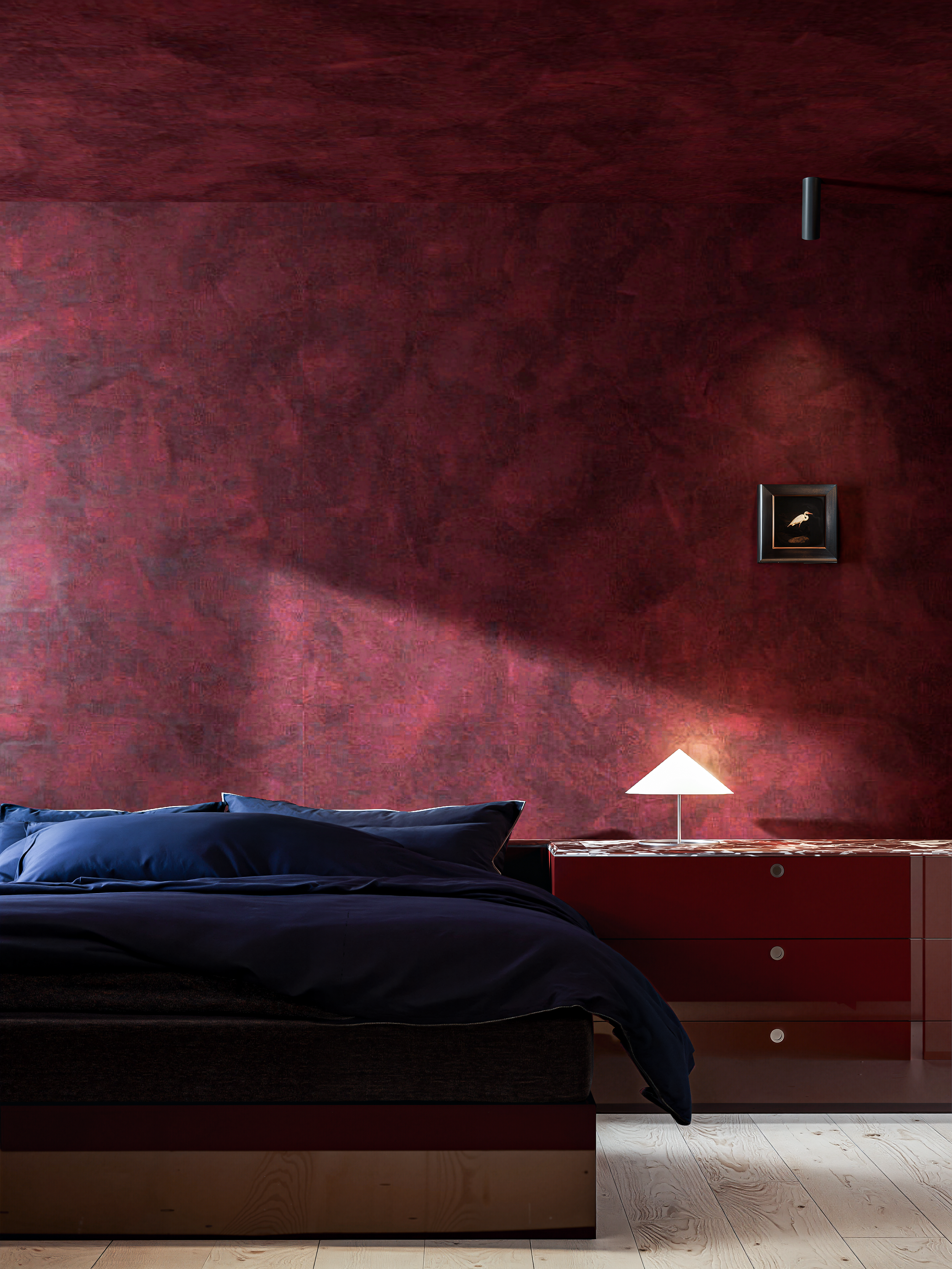 Moderne slaapkamer met donkerblauw beddengoed, rode muur, nachtkastje met lamp en muurkunstwerk met vogel