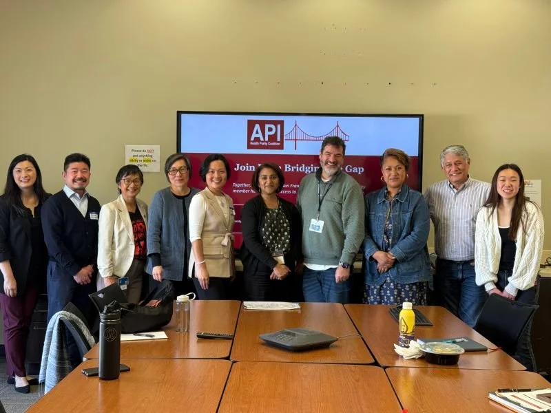 Group photo of APA Family Support Services team members standing together in front of an API banner celebrating 38 years of service in Chinatown.