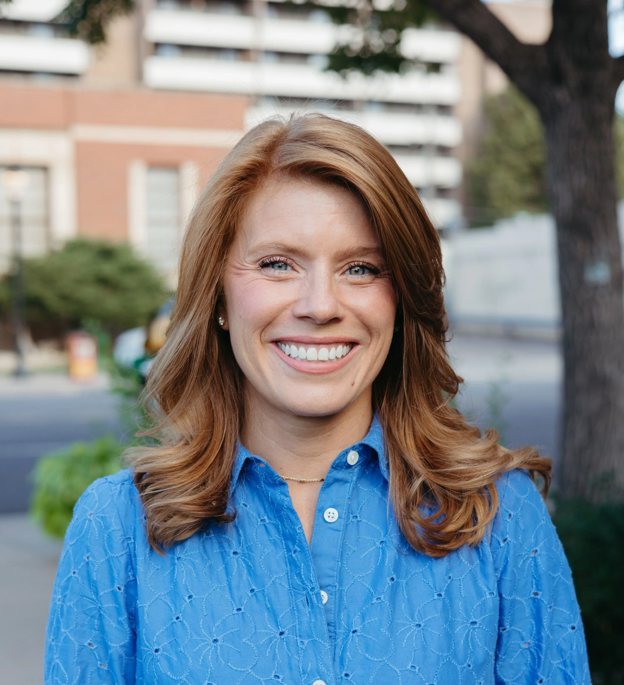 Headshot of Amber Peacher smiling at the camera outside CAFE 180