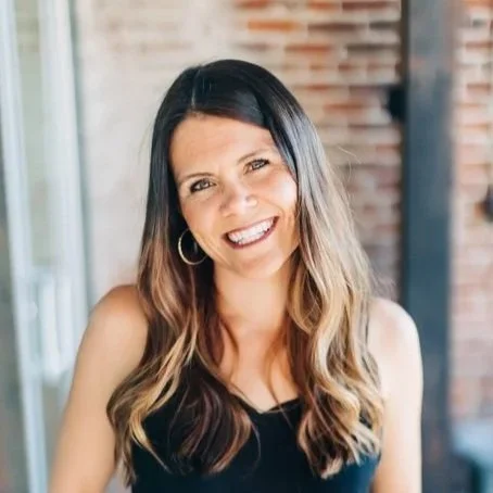 Headshot of CEO, Sarah Lesyinski smiling at the camera