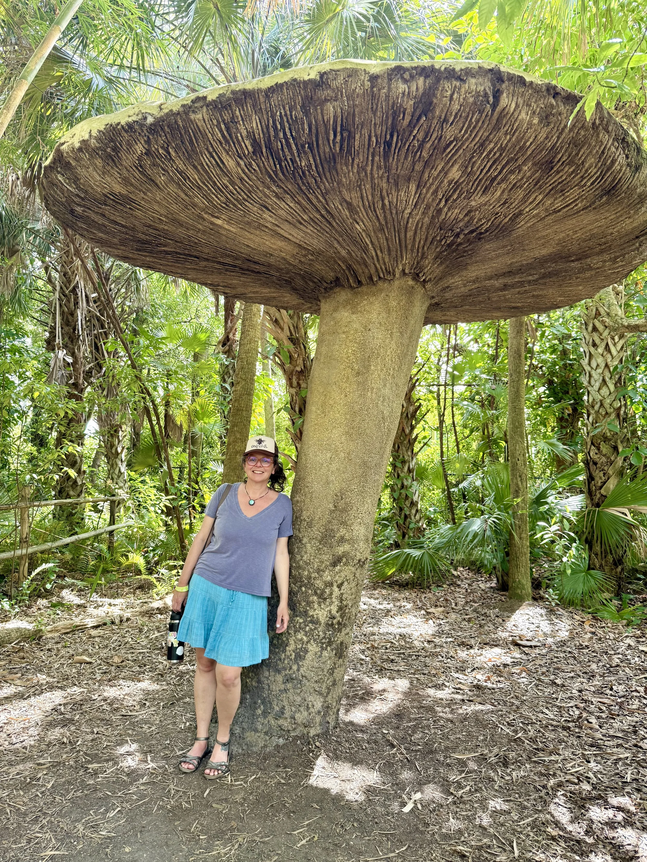 Jes leaning against a giant mushroom sculpture.