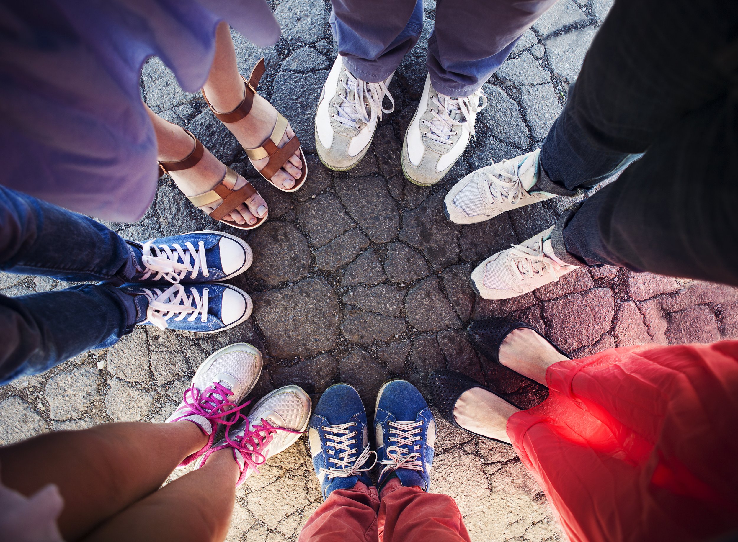 Looking down at the feet of a small group of people gathered in a circle.