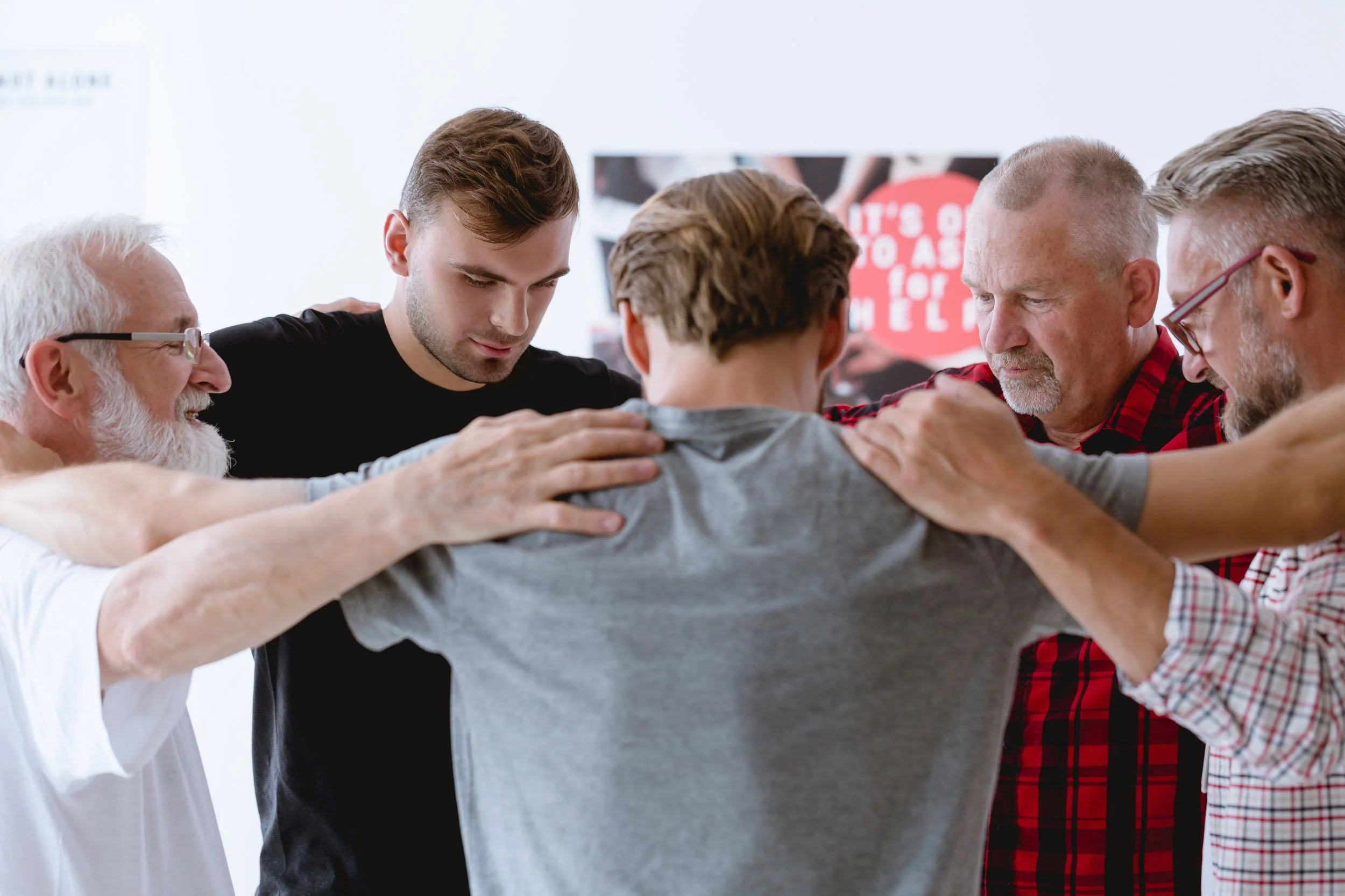 Group of men standing together, supporting each other, symbolizing connection, vulnerability, and growth in a safe and empowering environment.