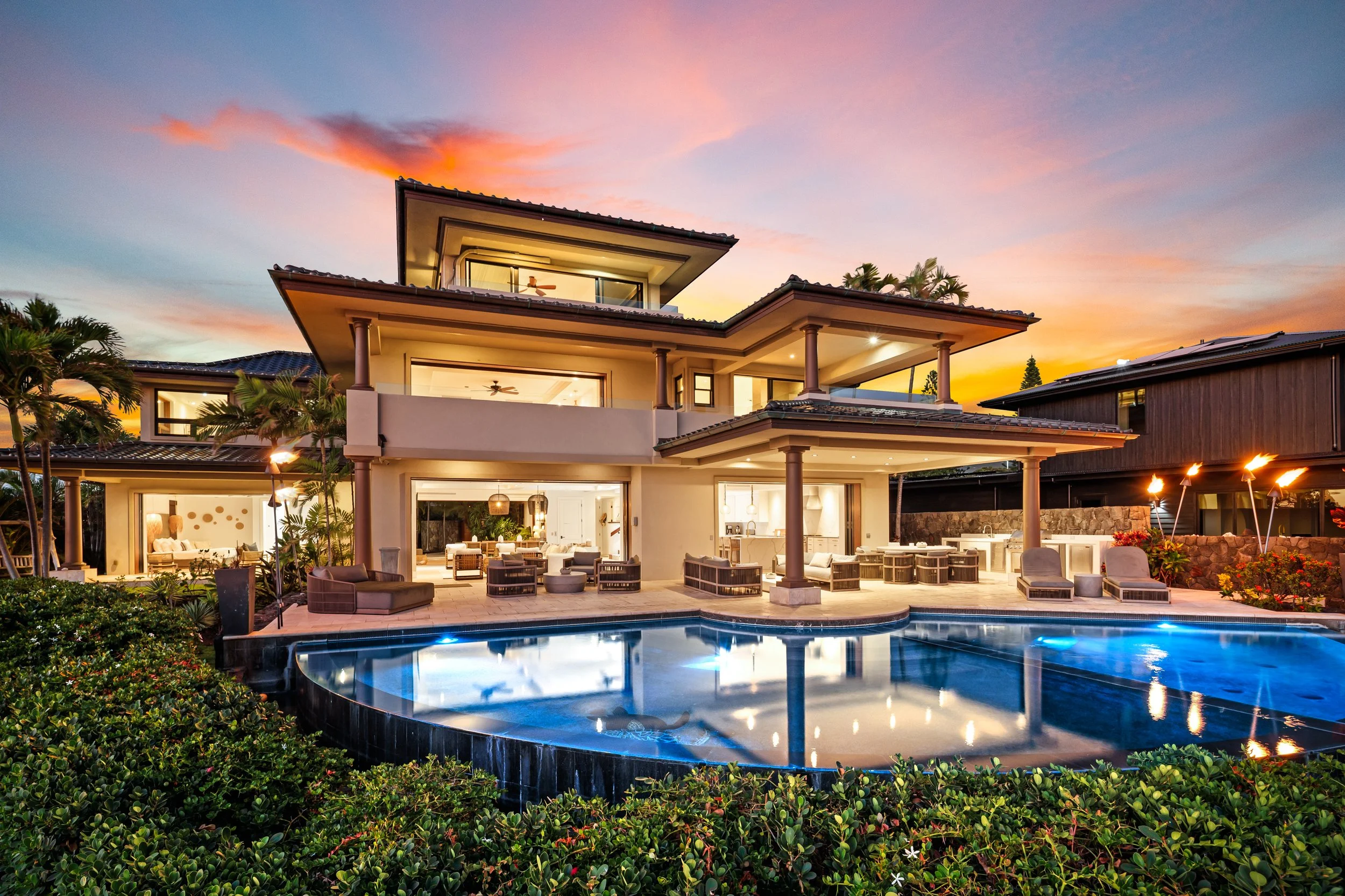 Luxury modern house with multiple levels, large windows, and a swimming pool in the backyard during sunset.