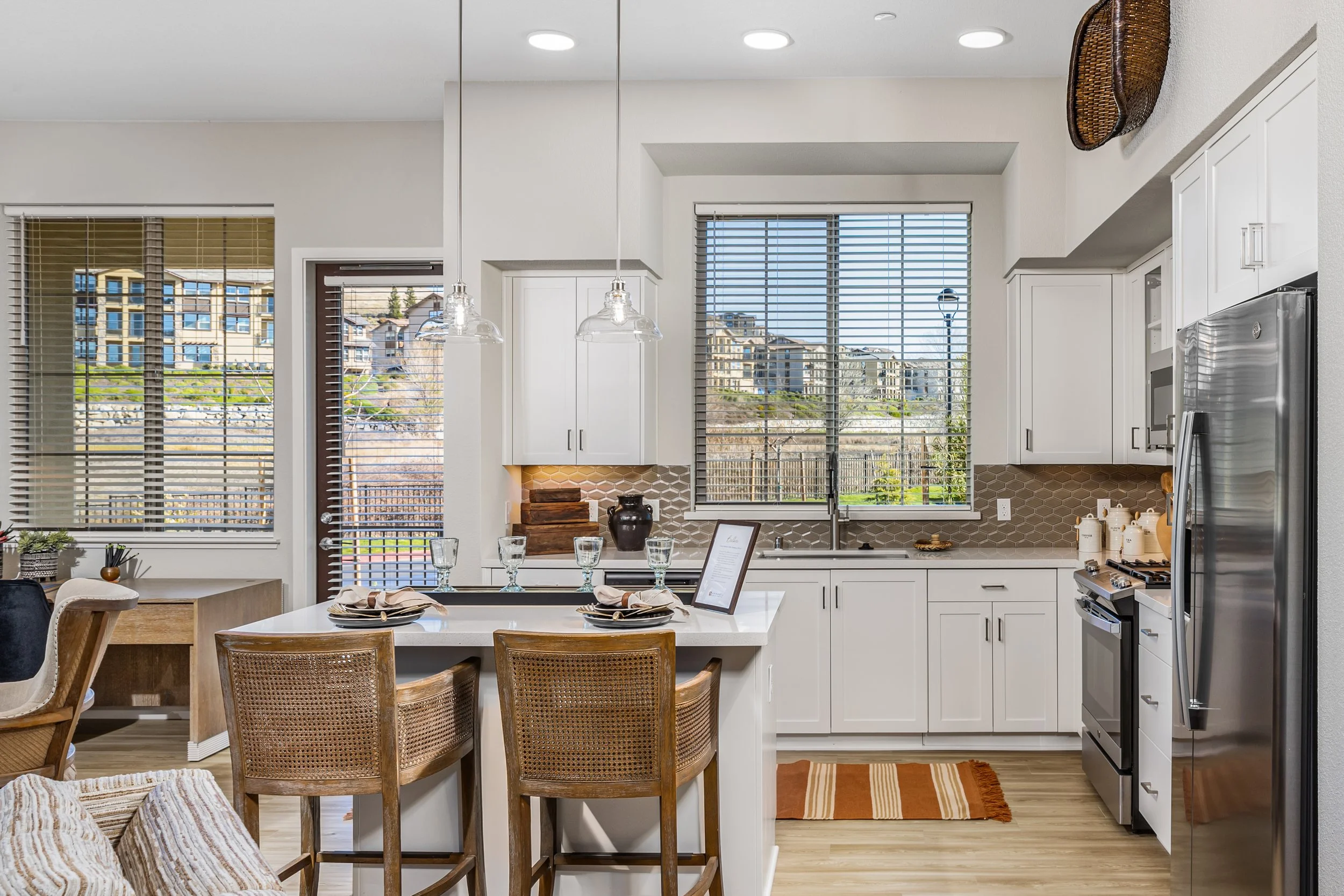 Bright kitchen with white cabinets, a large window, and a breakfast bar with chairs.