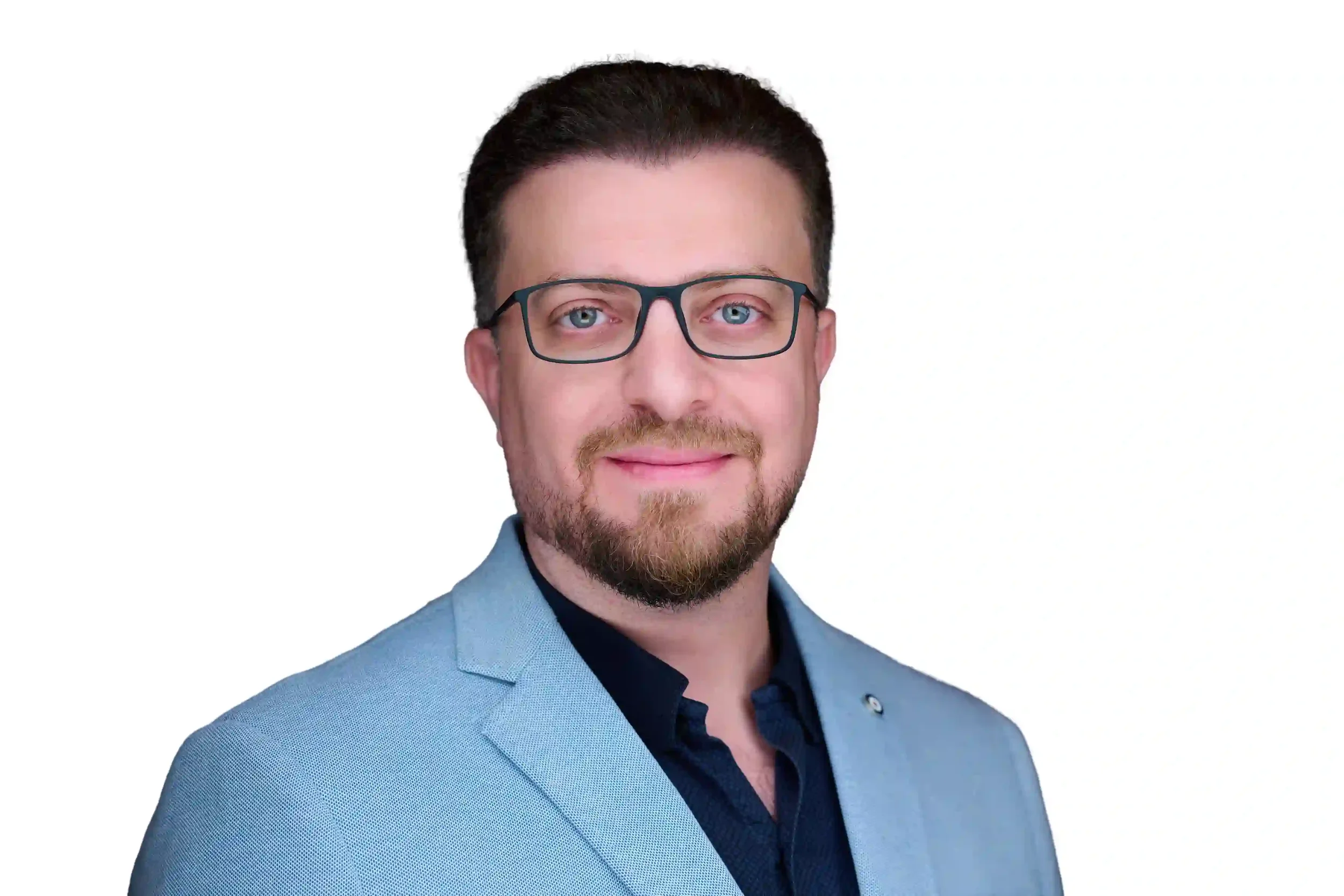 Professional headshot of a man with glasses, blue eyes, brown hair, and a beard, wearing a light blue blazer and navy shirt, against a white background.